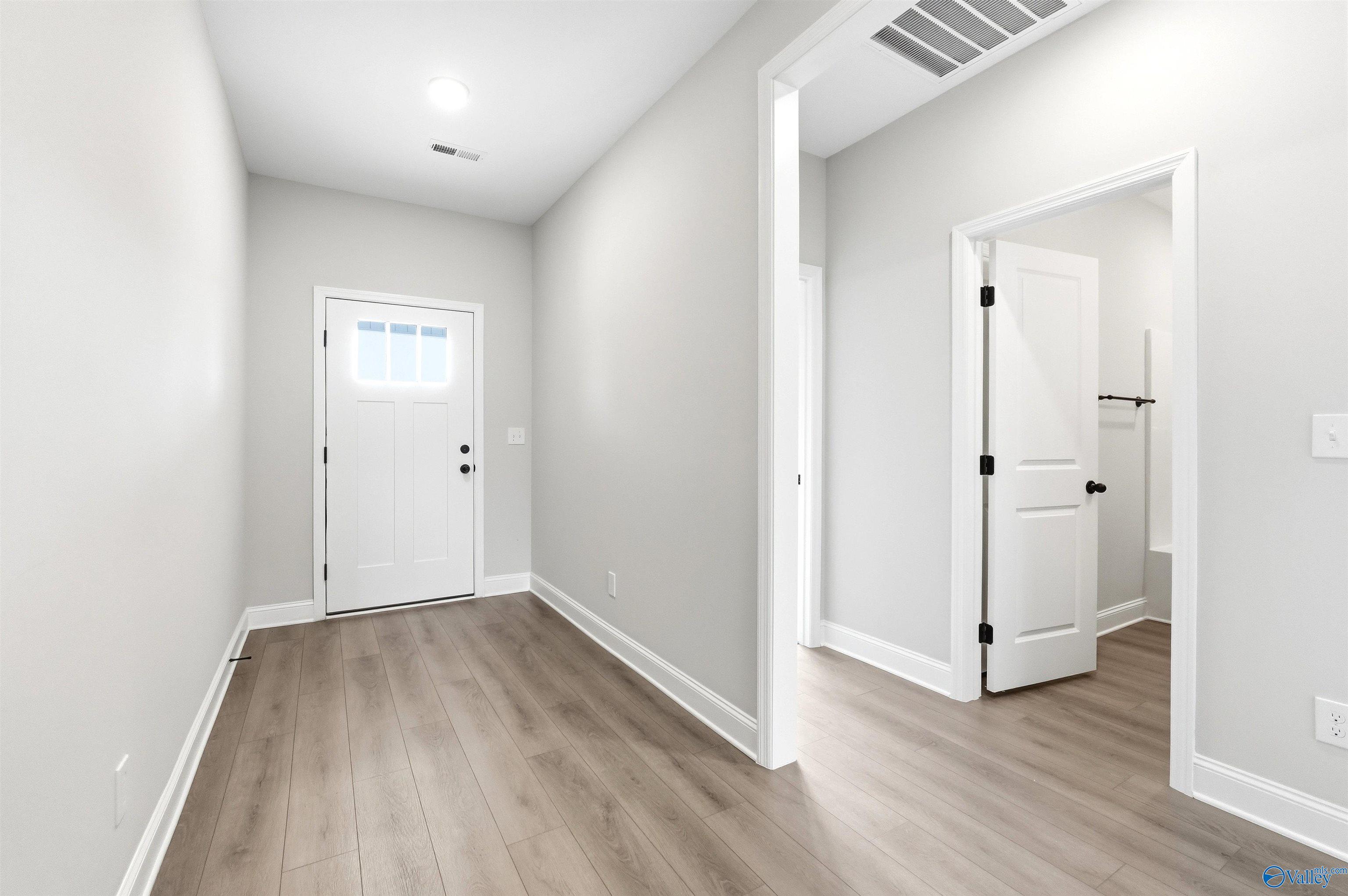 Bright entryway with light wood-style flooring and modern doors in The Daphne F plan at Berry Cove, New Market, AL.
