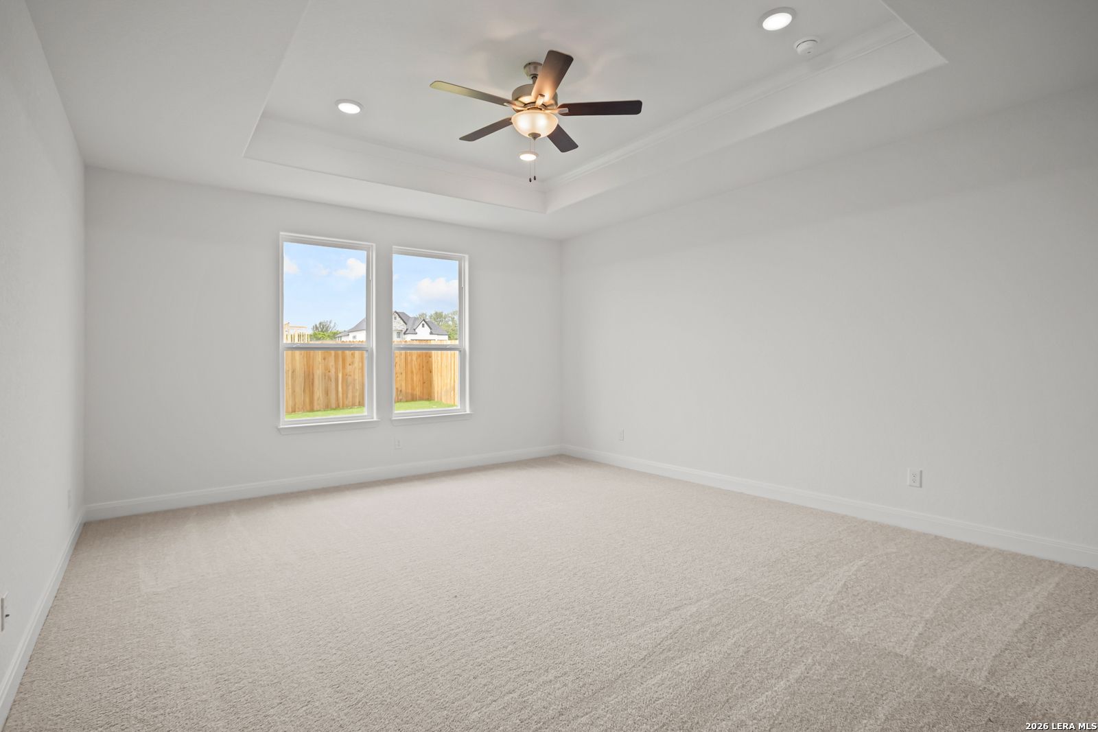 Spacious primary bedroom with tray ceiling and ceiling fan in The Lanier G floor plan at The Reserve at Potranco Oaks.