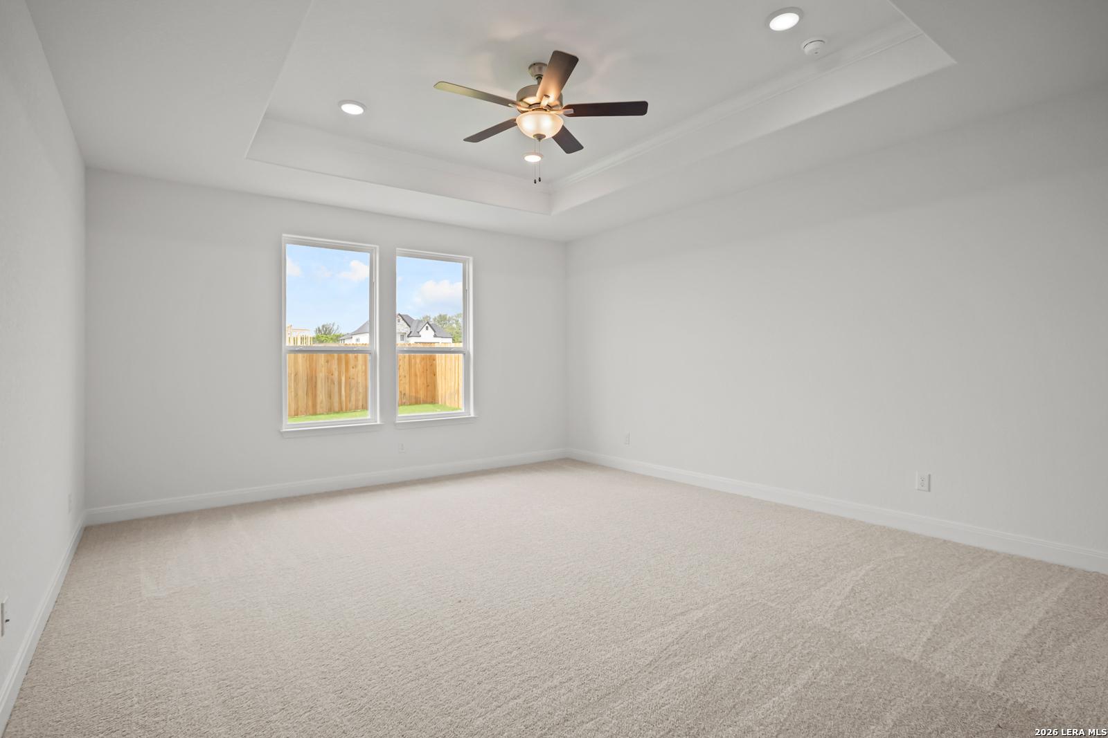 Spacious primary bedroom with tray ceiling and ceiling fan in The Lanier G floor plan at The Reserve at Potranco Oaks.