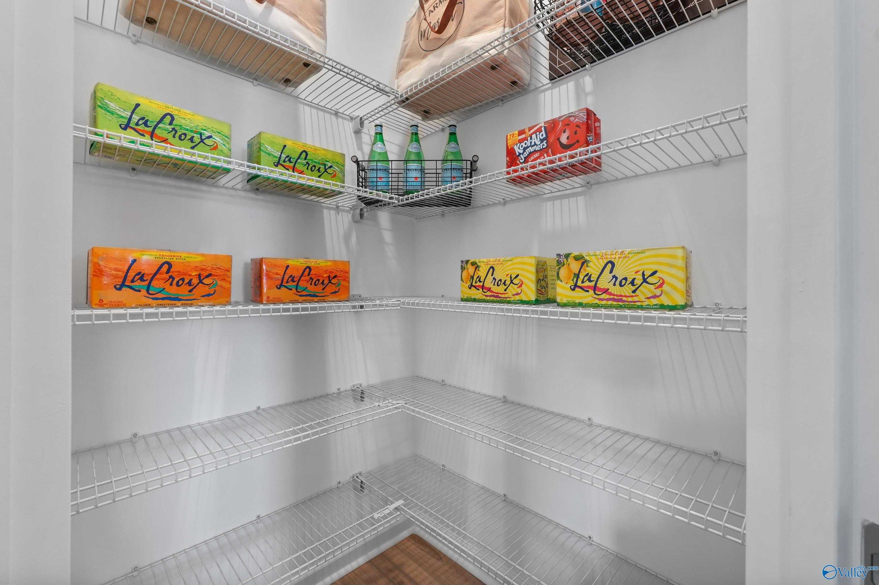 Spacious corner pantry with wire shelving stocked with La Croix sparkling water and snacks in Evermore Homes The Malibu, Madison, Alabama