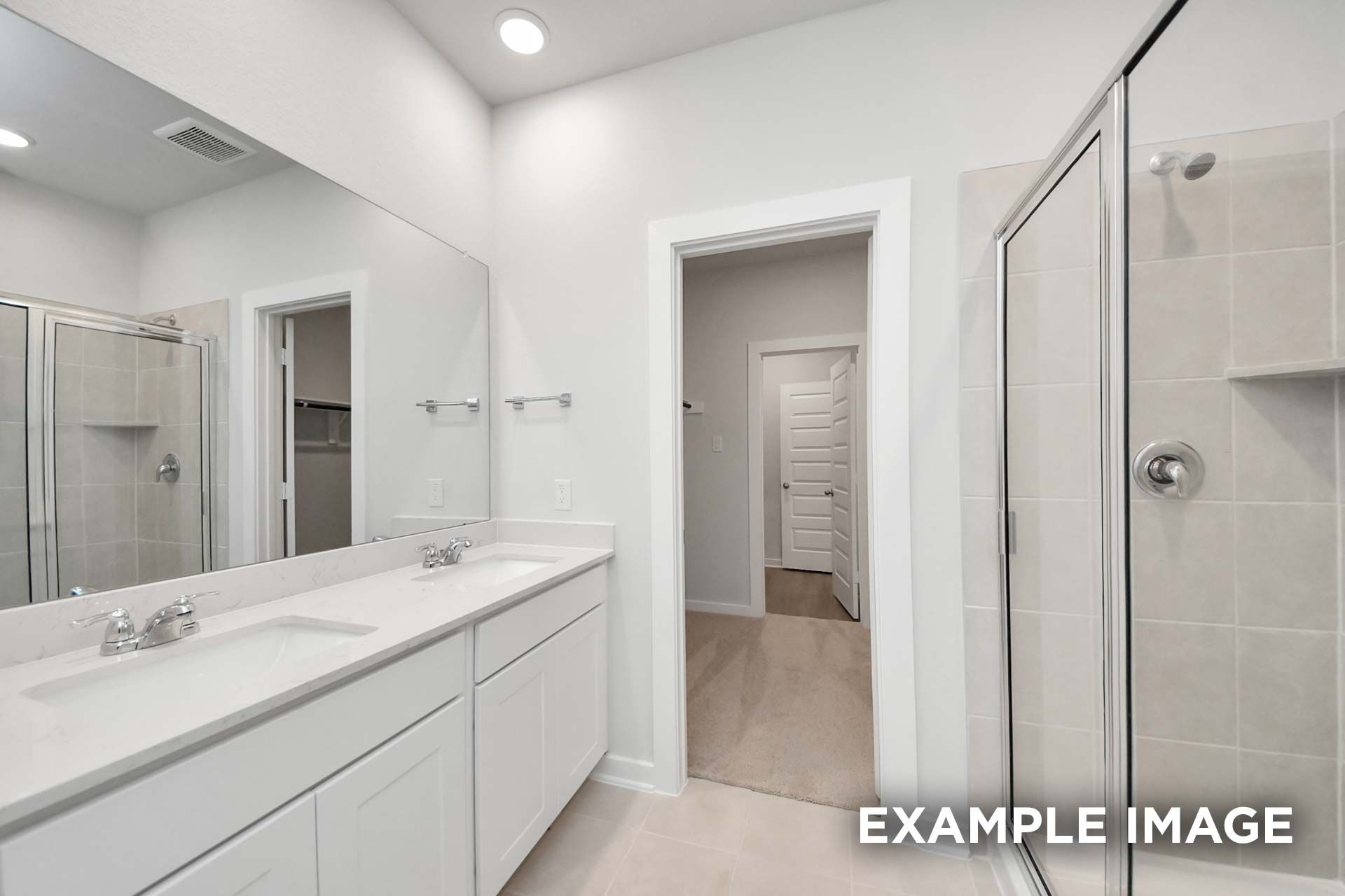Spacious master bathroom in The Blanco by Davidson Homes featuring dual vanities, glass shower, and large mirror