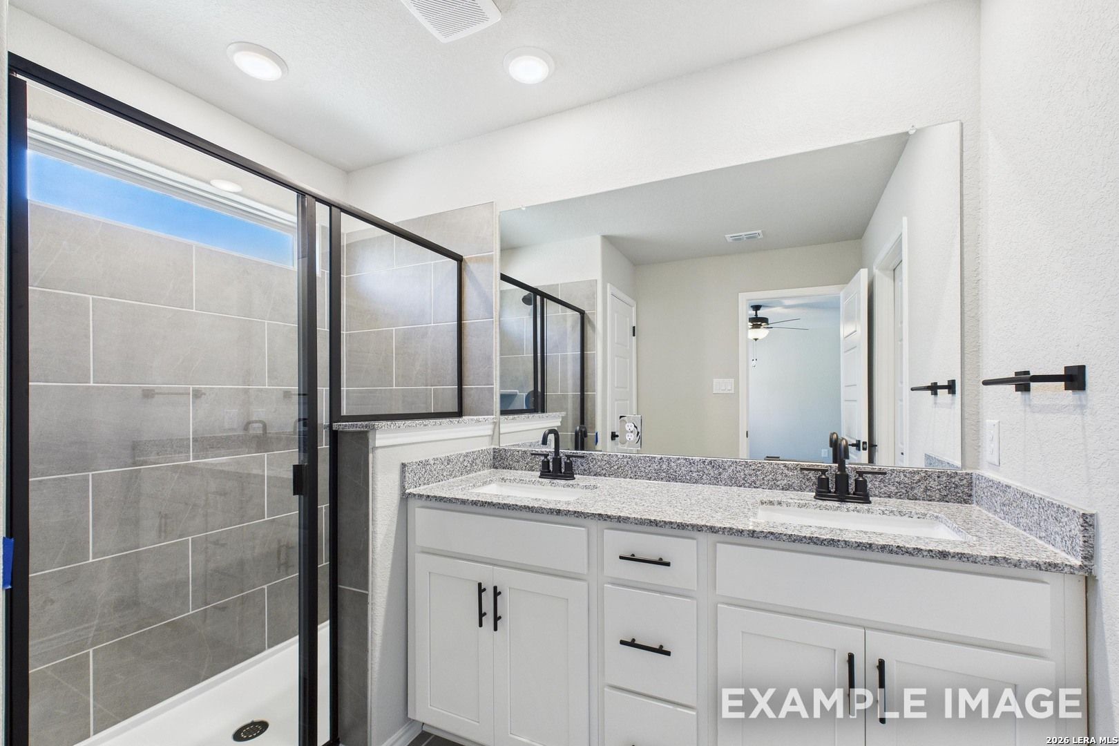 Modern bathroom with double vanity, granite countertops, and tiled walk-in shower in The Charlotte B, Cedar Heights, TX.