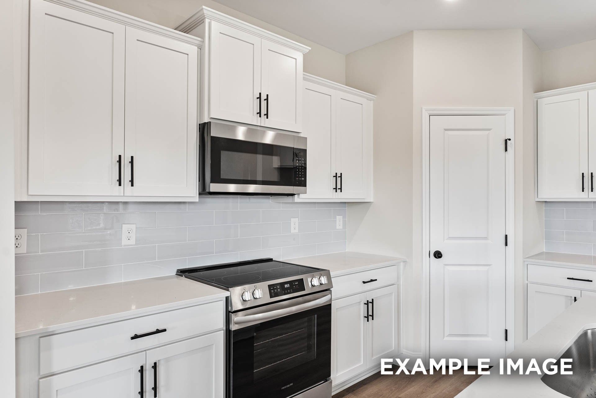 Modern kitchen with white cabinets, stainless steel appliances, and subway tile backsplash in The Franklin E, Bailey Park.