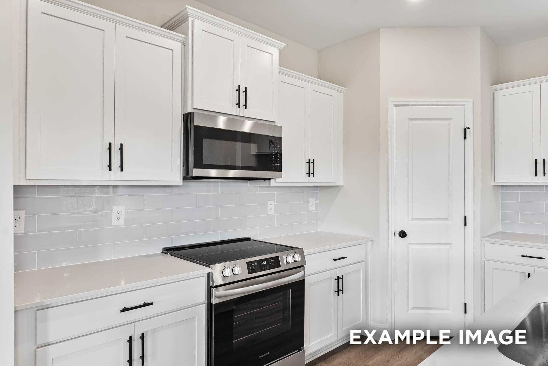 Modern kitchen with white cabinets, stainless steel appliances, and subway tile backsplash in The Franklin E, Bailey Park.