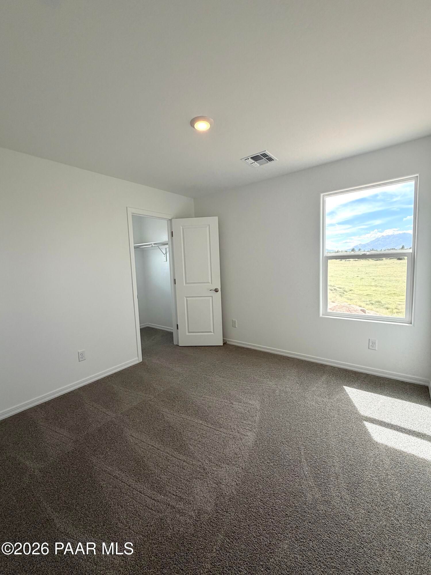 Bright bedroom with plush carpet, walk-in closet, and scenic mountain views in Davidson Homes The Raleigh A, Prescott, AZ.
