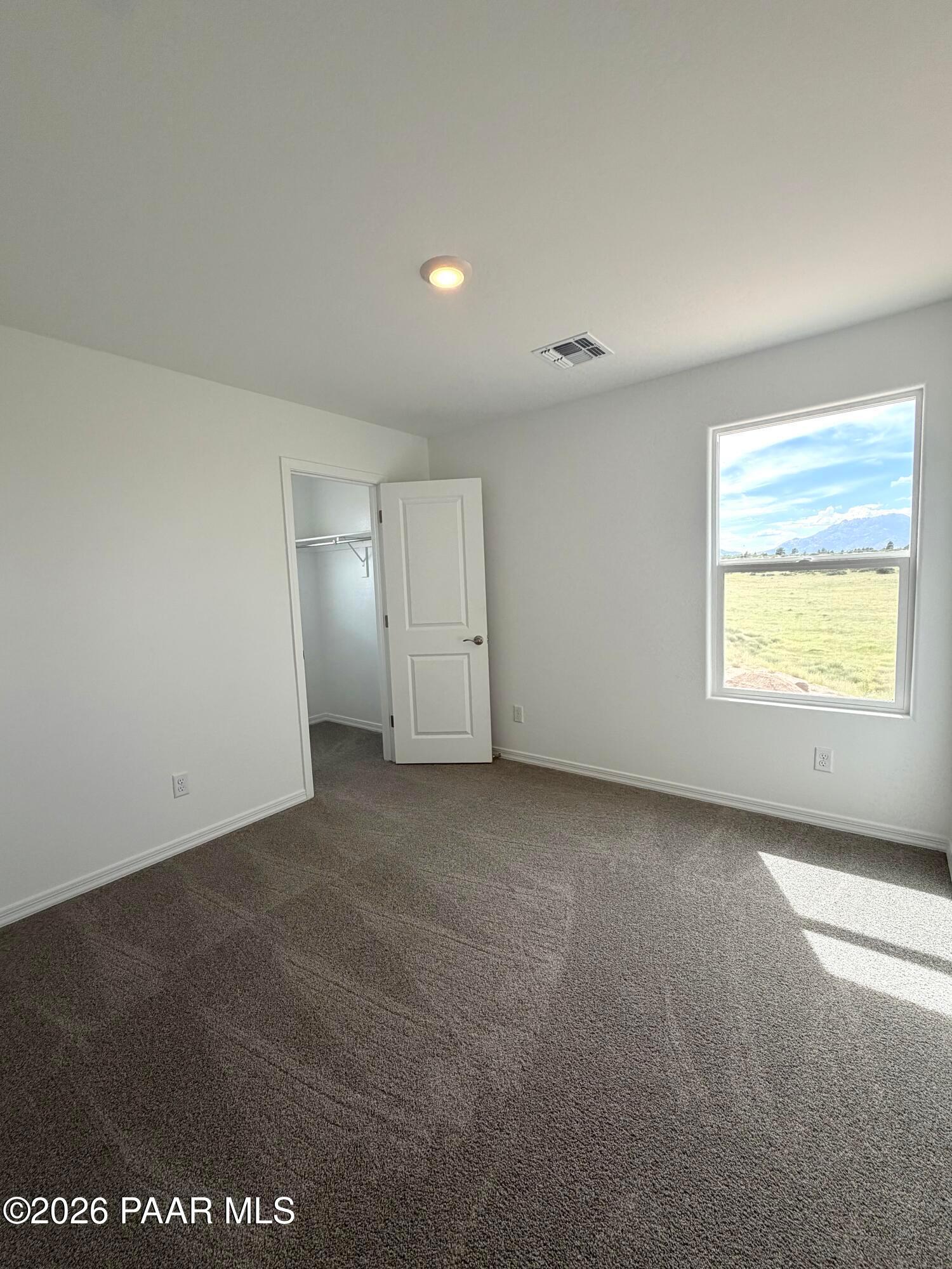 Bright bedroom with plush carpet, walk-in closet, and scenic mountain views in Davidson Homes The Raleigh A, Prescott, AZ.