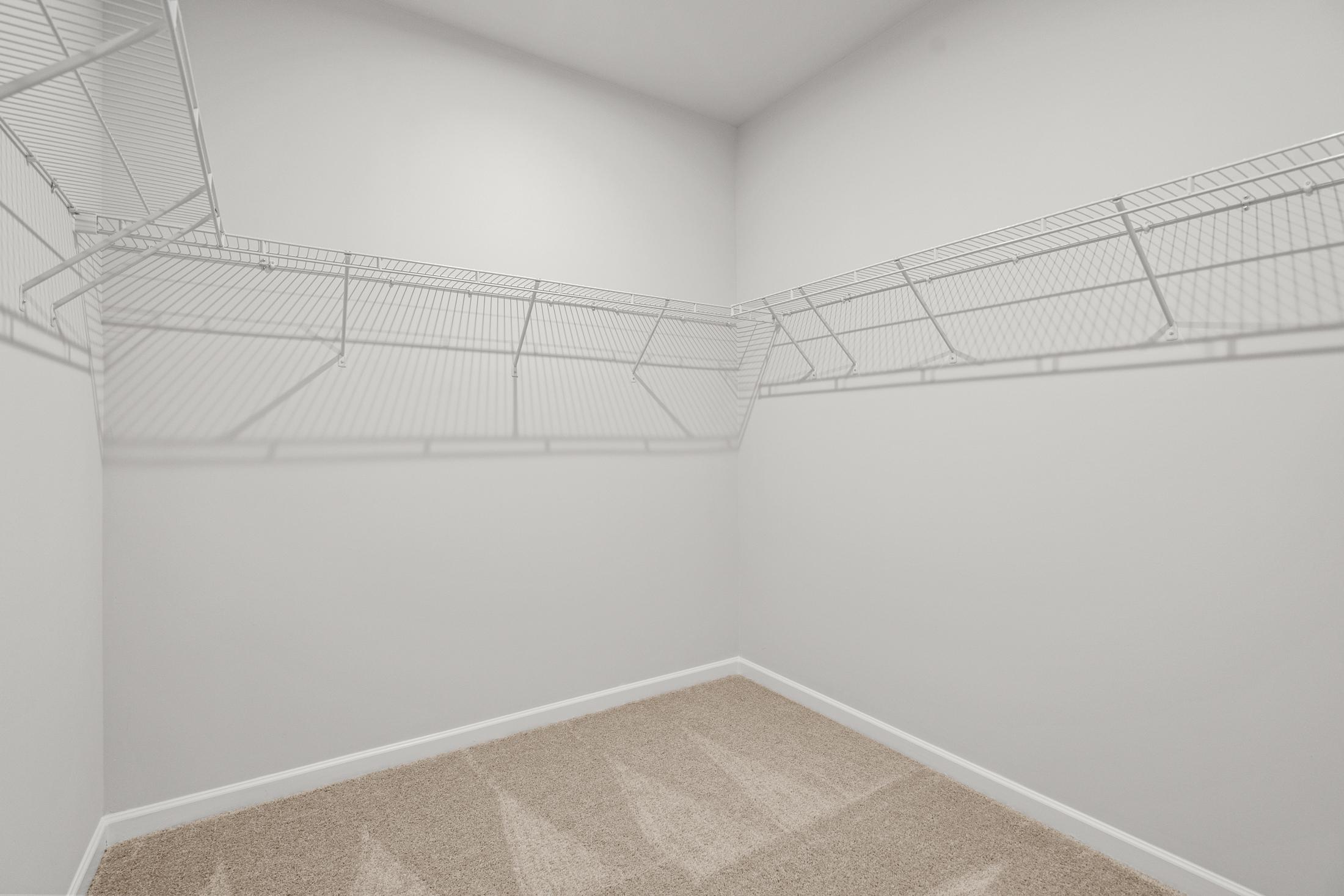 Spacious walk-in closet in The Ash B master suite at Wehunt Meadows featuring wire shelving and beige carpet