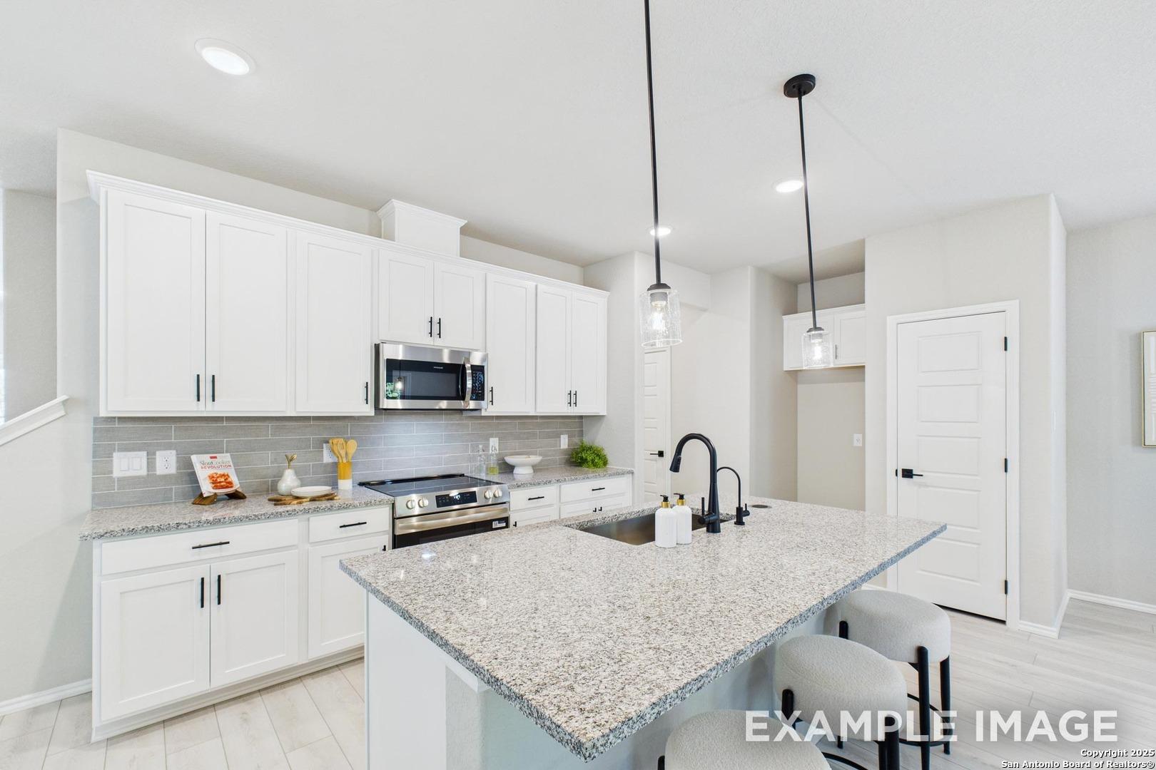 Modern white kitchen with granite island, stainless appliances, subway tile in Davidson Homes The Charlotte B, San Antonio