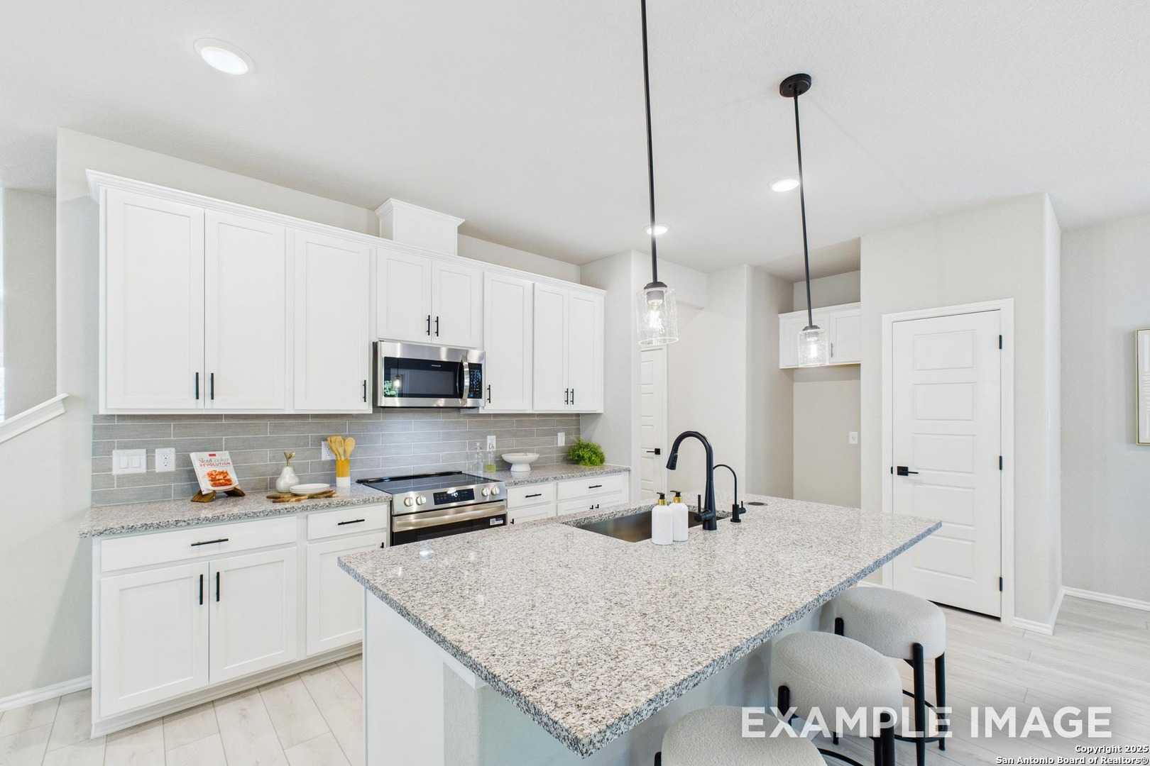 Modern white kitchen with granite island, stainless appliances, subway backsplash in Davidson Homes The Charlotte A, San Antonio