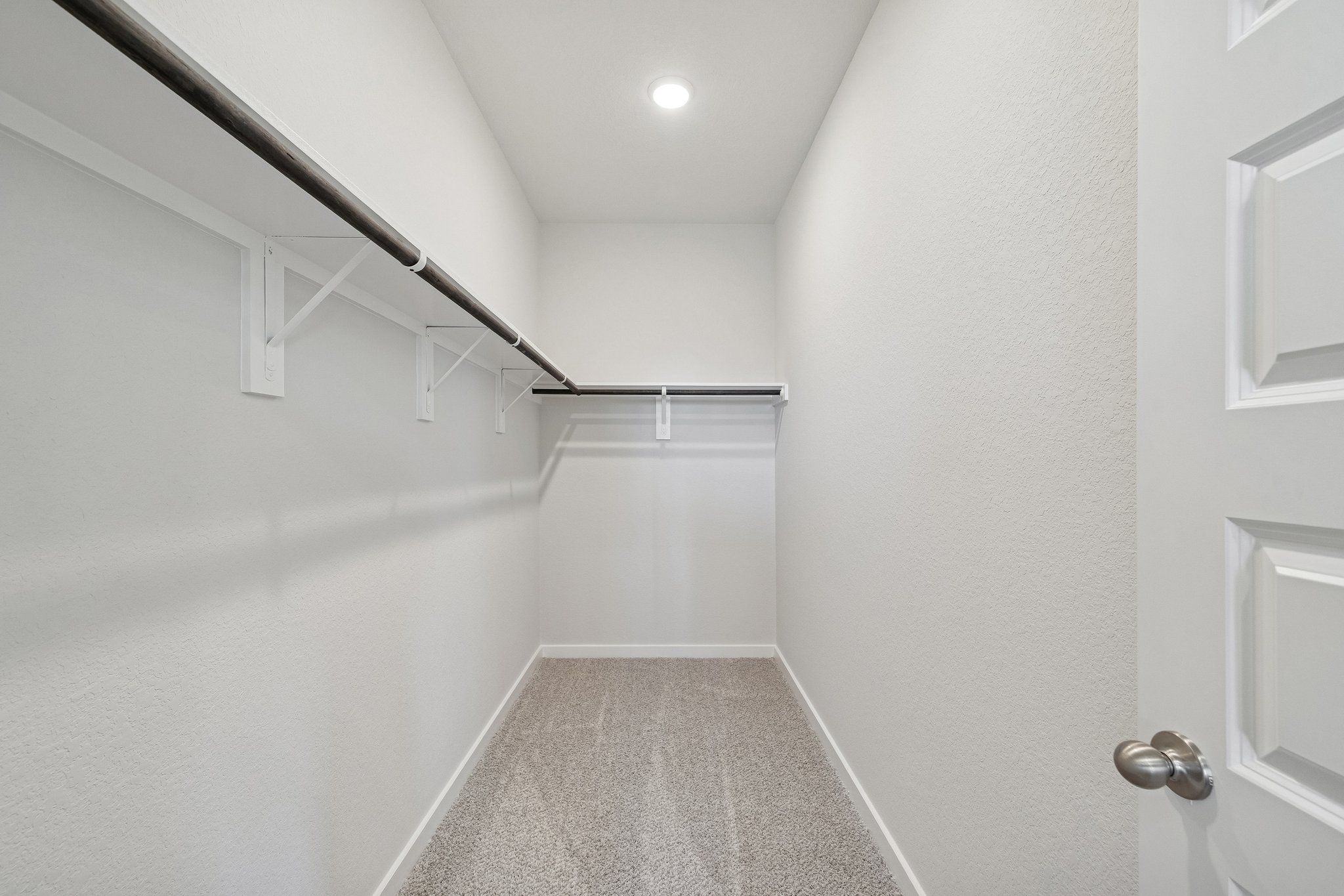 Spacious walk-in closet at Spring Branch Crossing in Conroe TX with white walls, double hanging rods, and carpeted floor