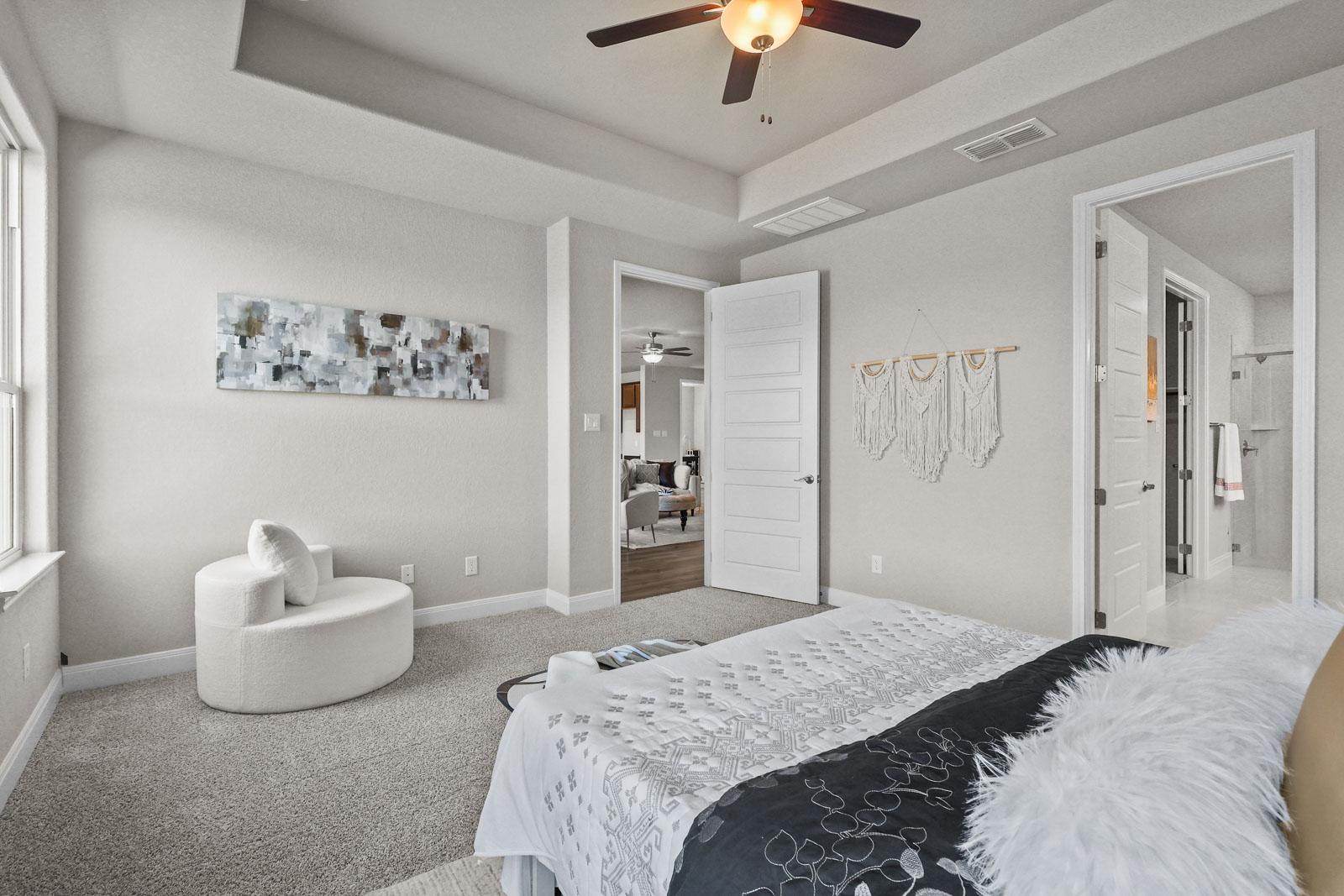 Spacious master suite on the main floor of The Jennings G featuring a tray ceiling, plush carpeting, and private bath.