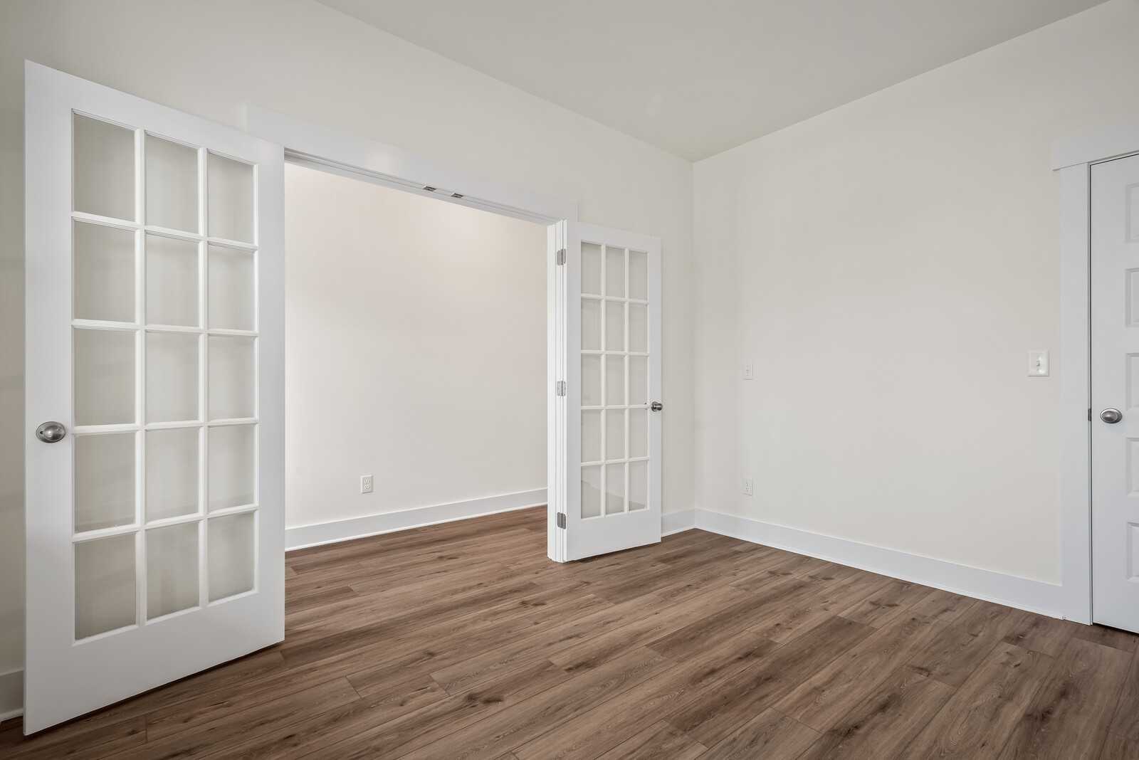 Open French doors with glass panels leading to empty room, hardwood floors, in Davidson Homes The Logan C, Gallatin, Tennessee