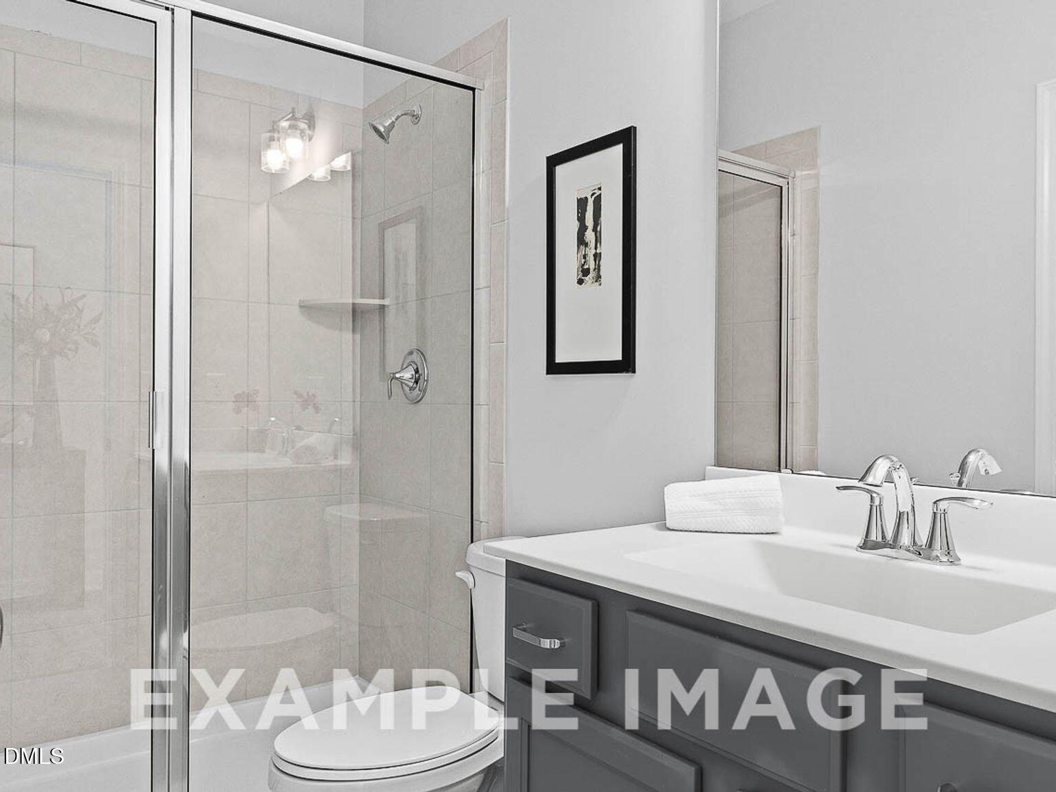Modern master bathroom with frameless glass shower, double vanity sink, and neutral tones in Davidson Homes The Chestnut B, Lillington, NC