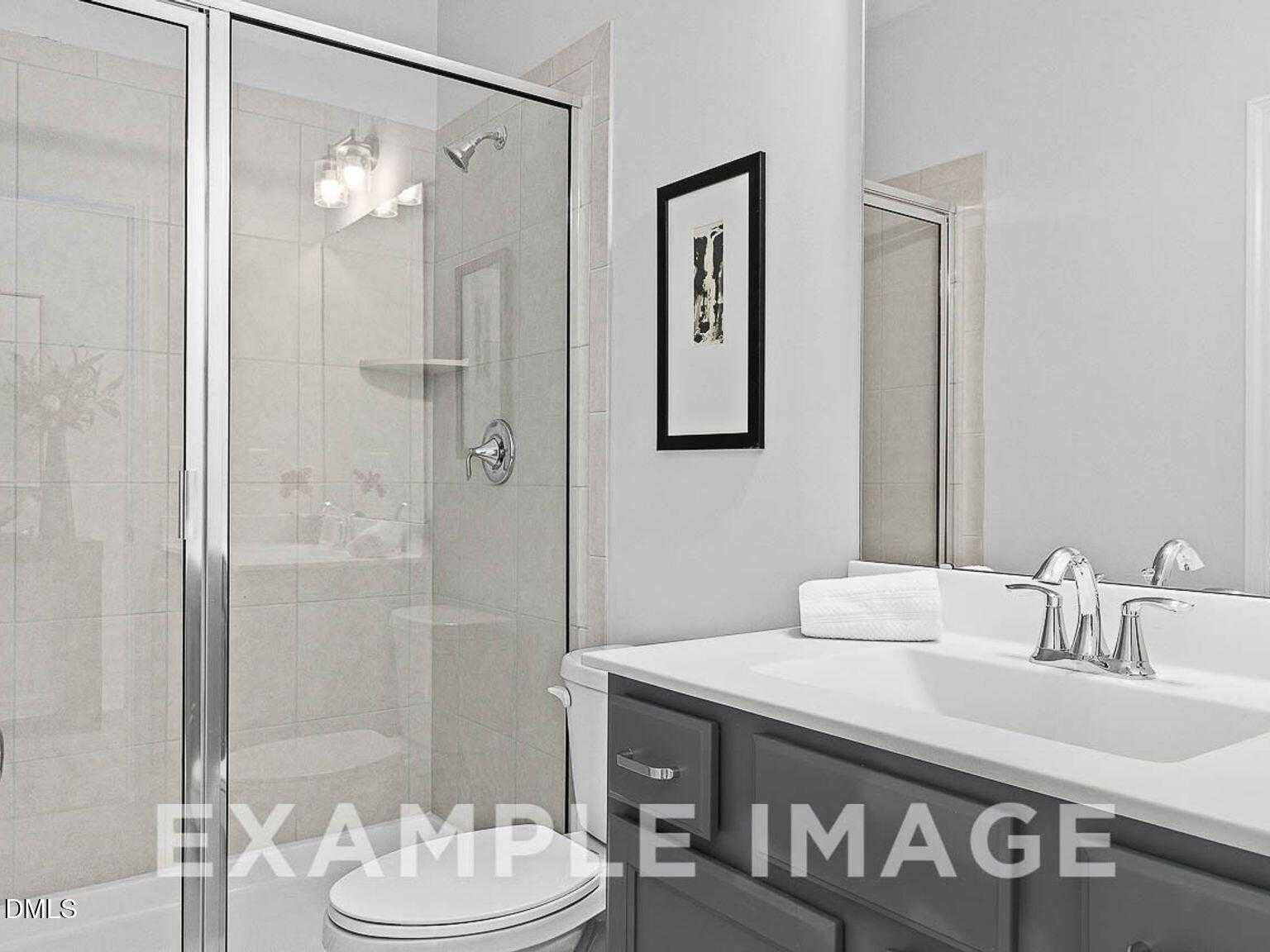 Modern master bathroom with frameless glass shower, double vanity sink, and neutral tones in Davidson Homes The Chestnut B, Lillington, NC