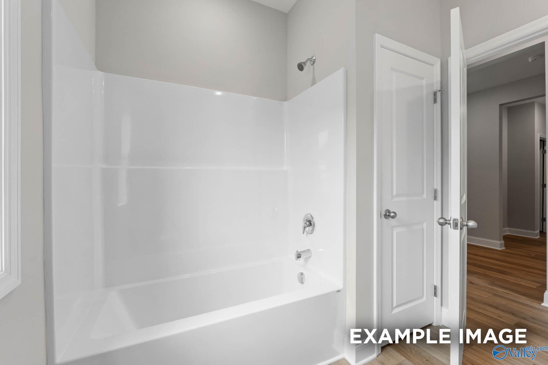 Modern white bathtub and glass-enclosed shower in guest bath, Davidson Homes The Everett floor plan, Meridianville, Alabama