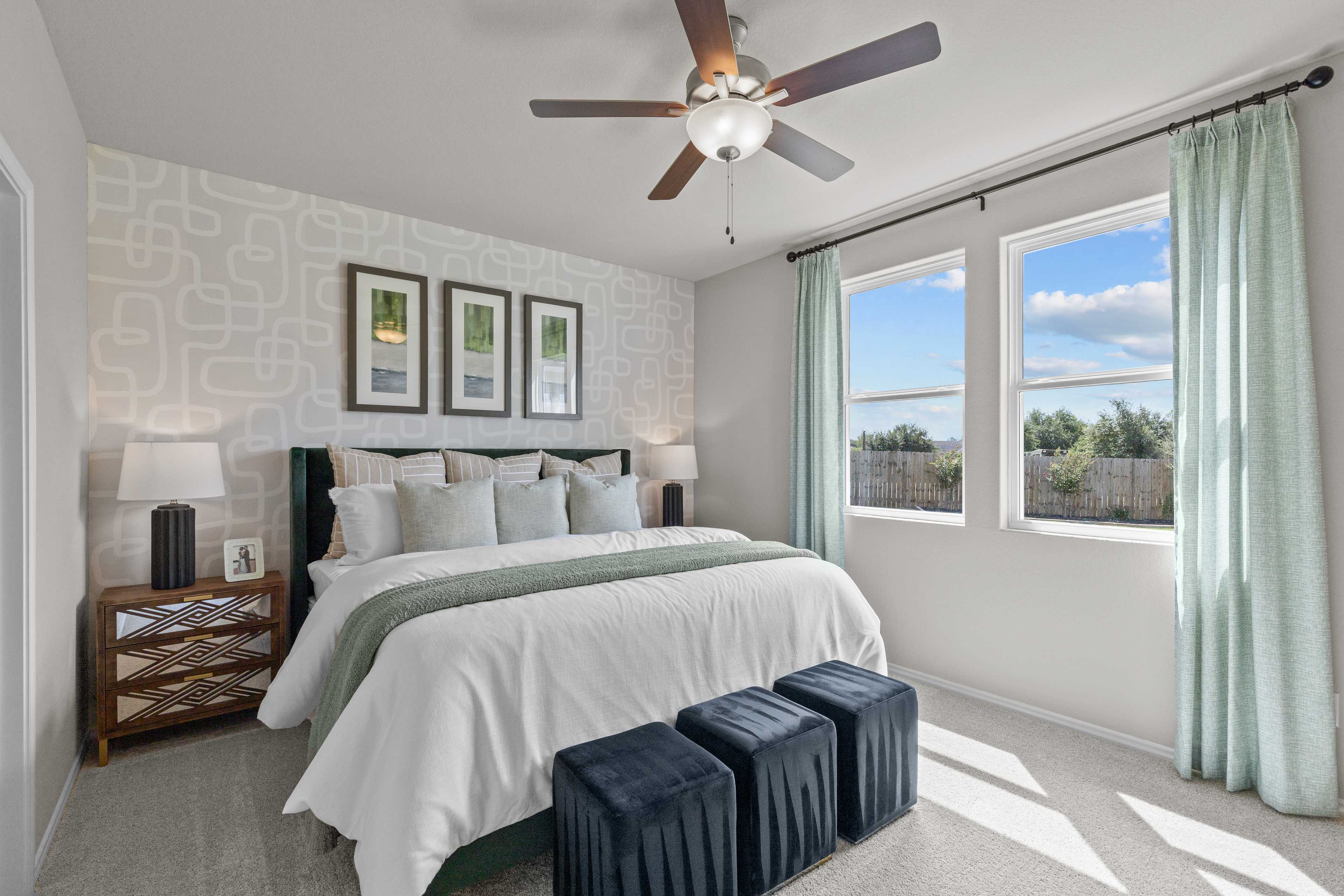 Spacious primary bedroom at Comanche Ridge in San Antonio TX with king bed, ceiling fan, and large windows