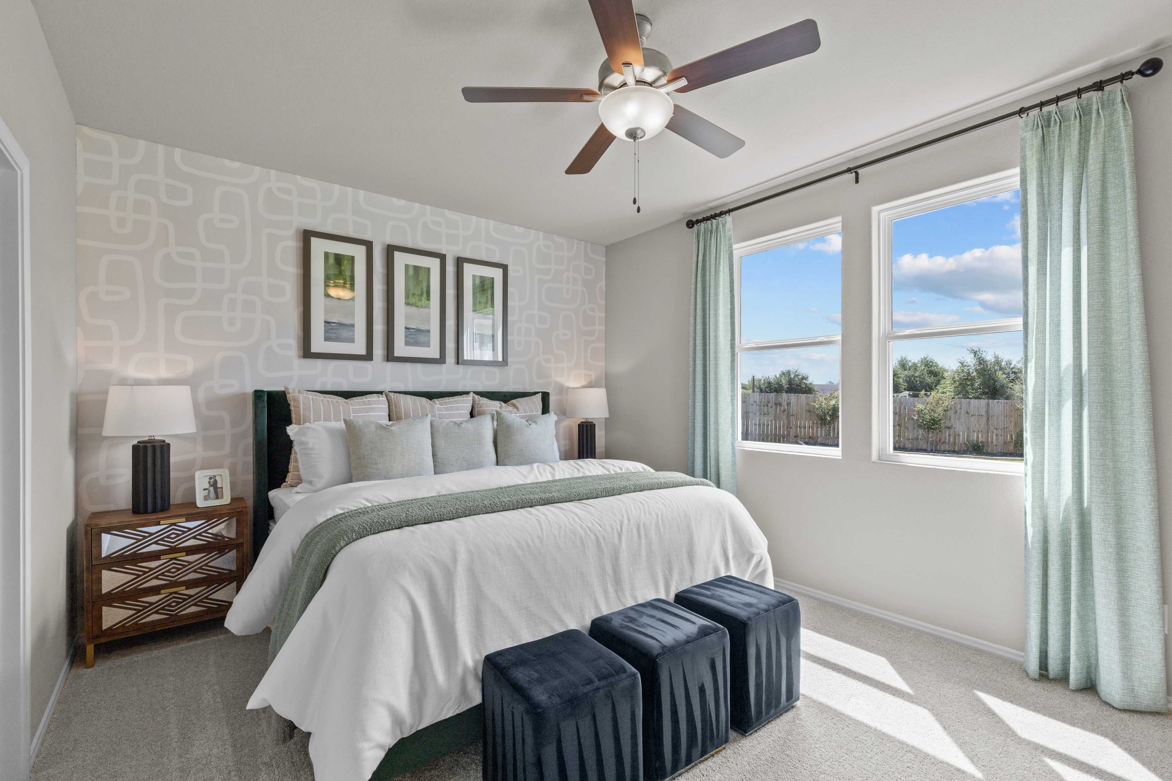 Spacious primary bedroom at Comanche Ridge in San Antonio TX with king bed, ceiling fan, and large windows