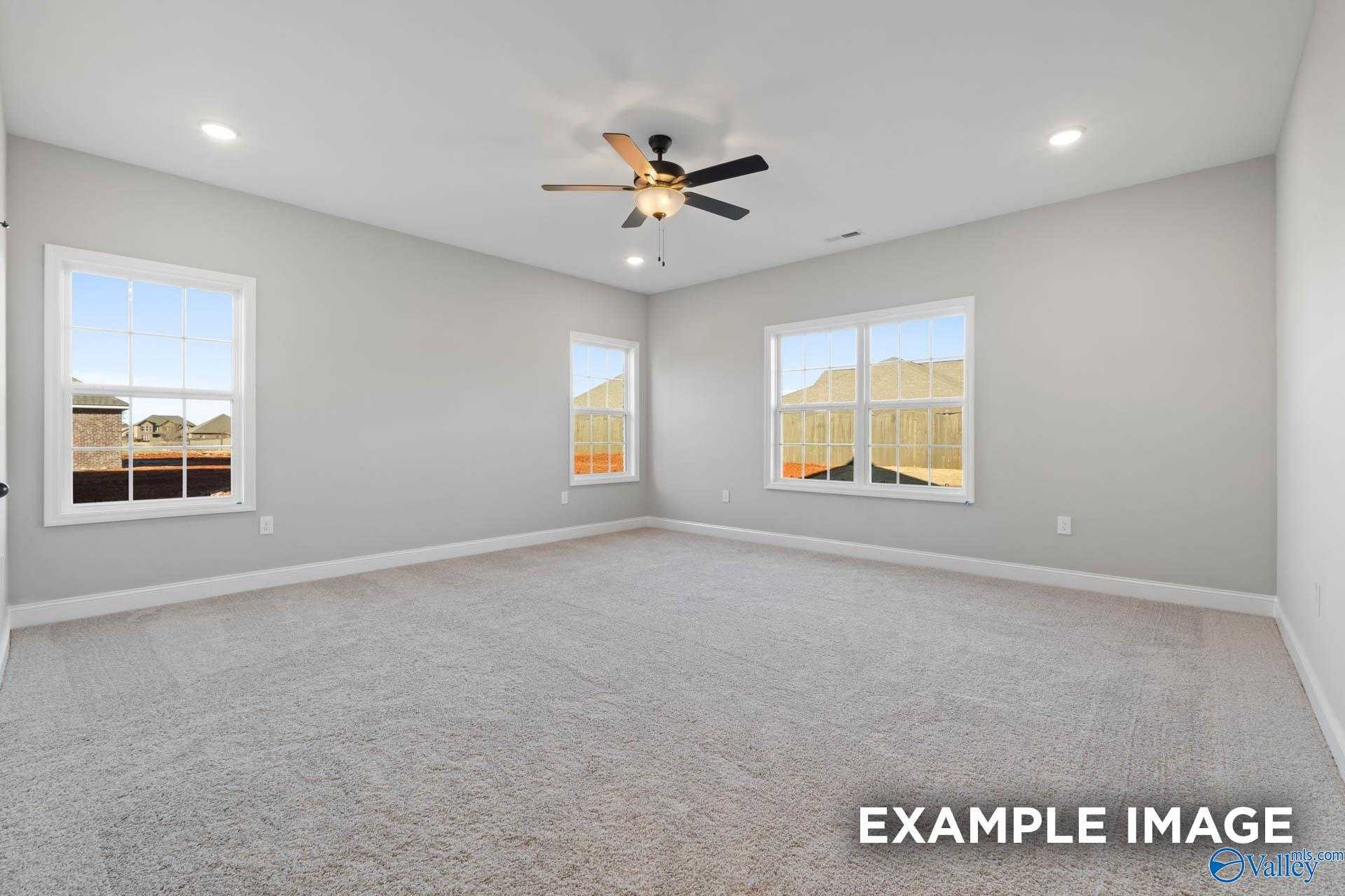 Bright bedroom with light gray walls, large windows, ceiling fan, and plush carpet in Davidson Homes The Valencia, Meridianville, Alabama