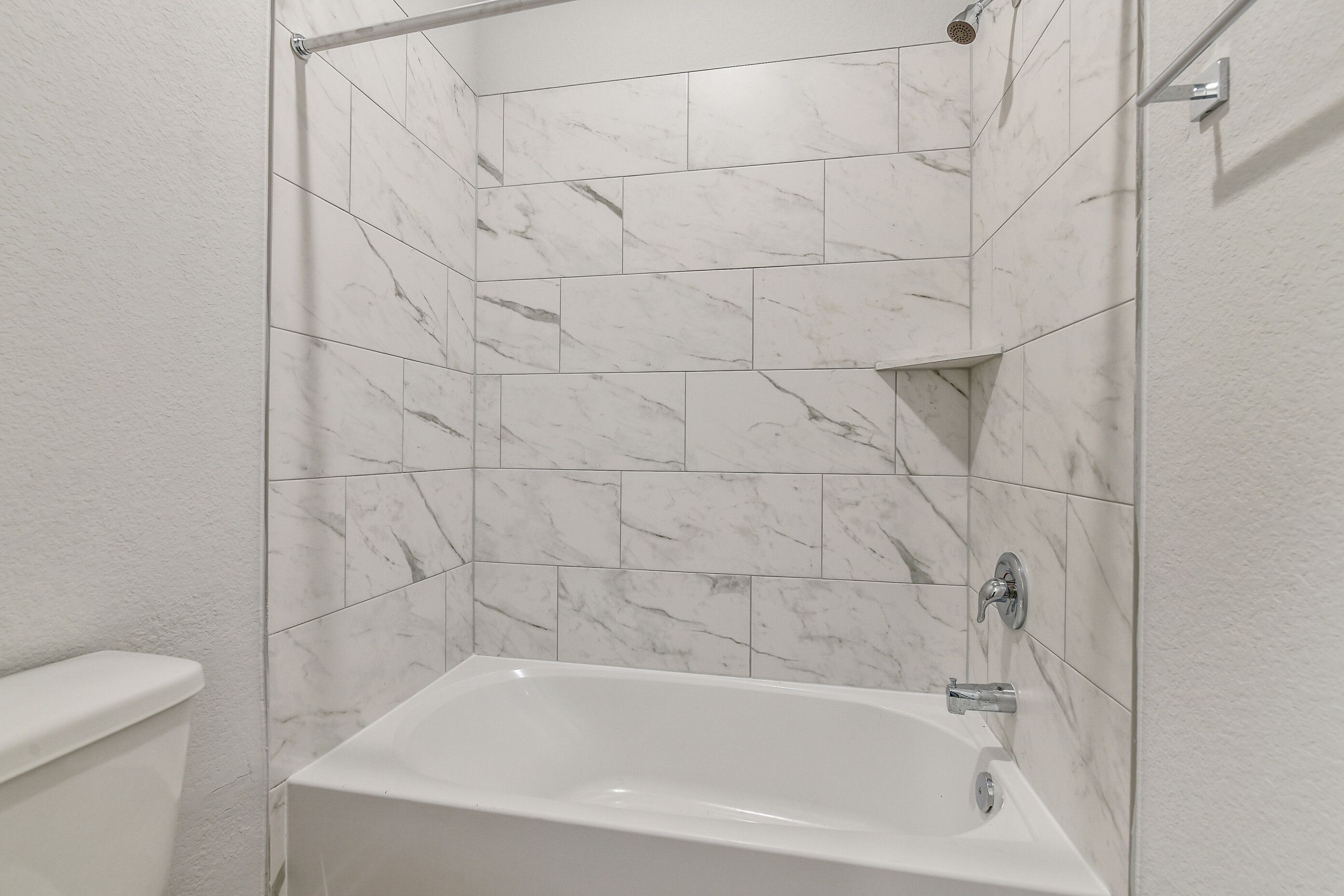 Elegant white marble tiled shower enclosure and deep soaking tub in modern bathroom, Davidson Homes The Colorado G, Magnolia Texas