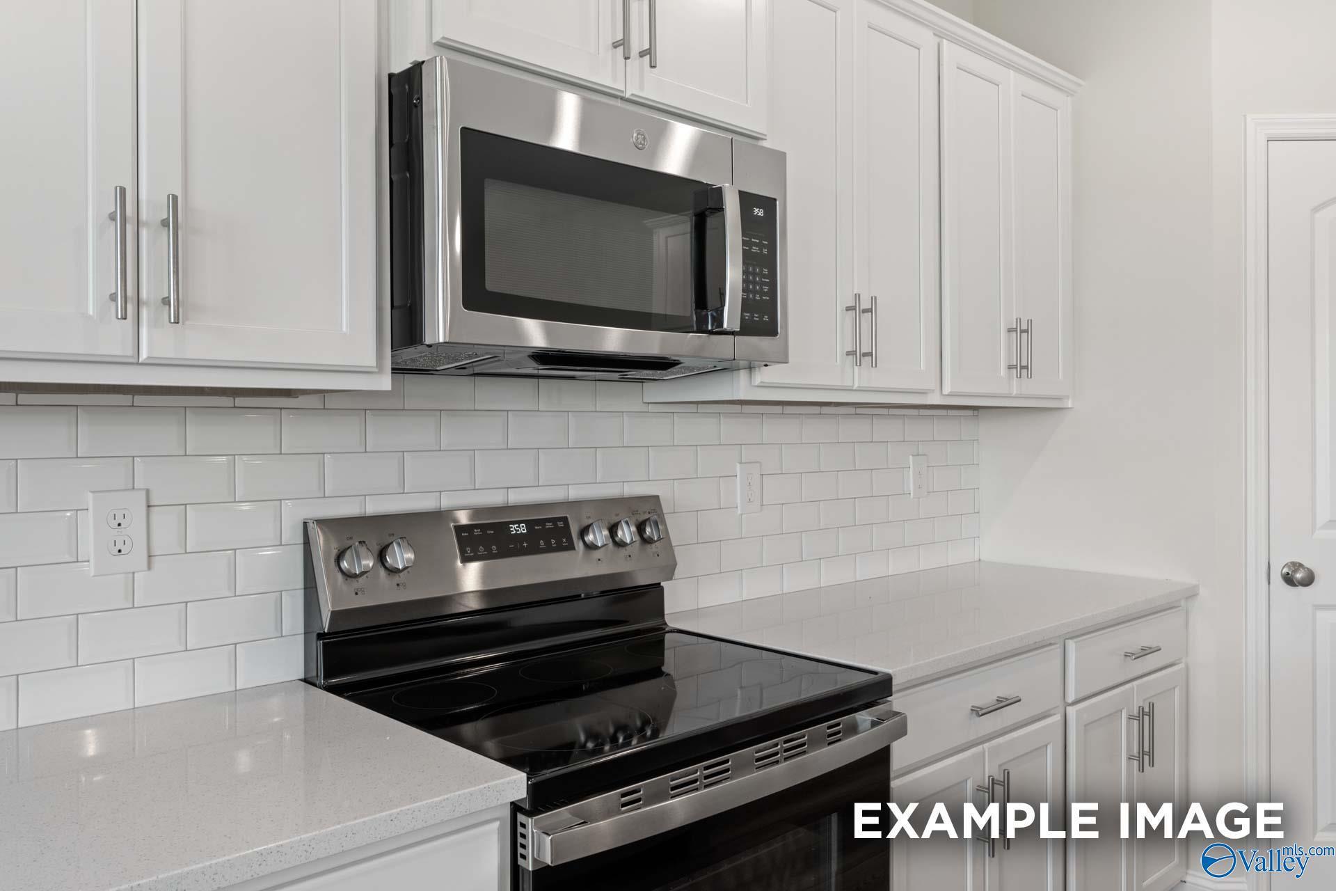 Modern kitchen with white cabinets, stainless steel appliances, and subway tile backsplash in The Madison A floor plan.
