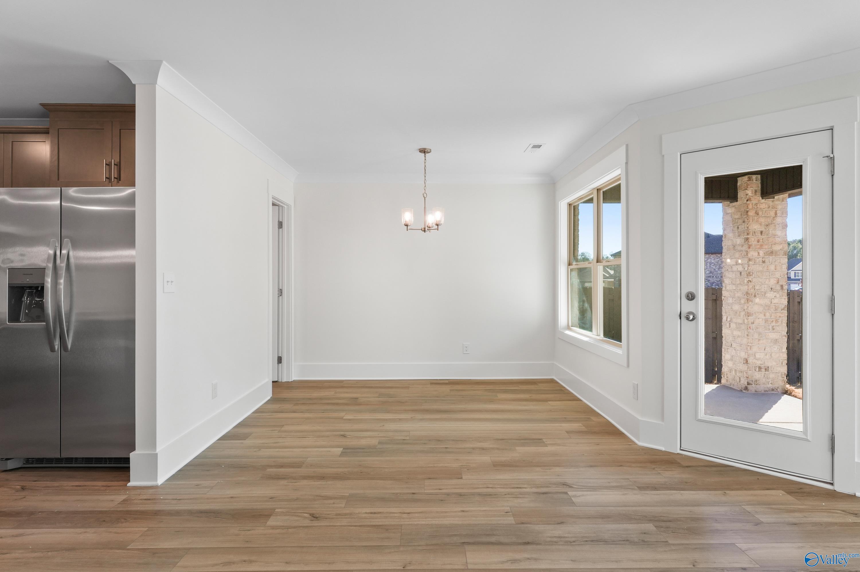 Elegant dining room with chandelier, hardwood floors, large windows, and French doors in Davidson Homes The Daphne C, Arab, Alabama