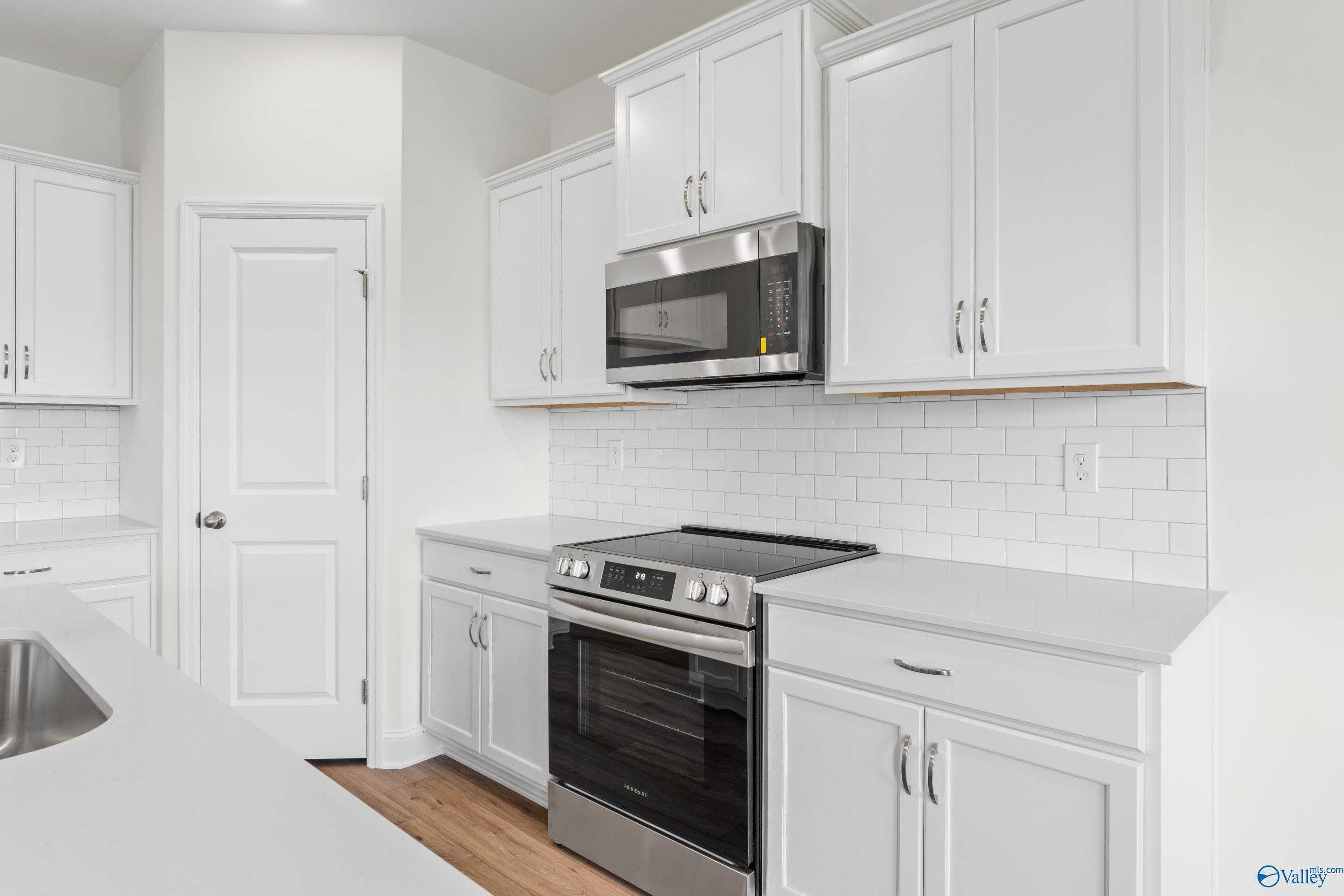 Modern white kitchen with stainless steel appliances, subway tile backsplash, and island in Davidson Homes The Asheville C, Hazel Green, Alabama