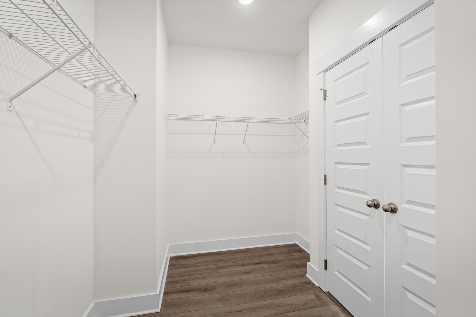 Walk-in closet with white wire shelving and wood-style flooring in The Ridgeport D at Benders Cove, Mt. Juliet, Tennessee.