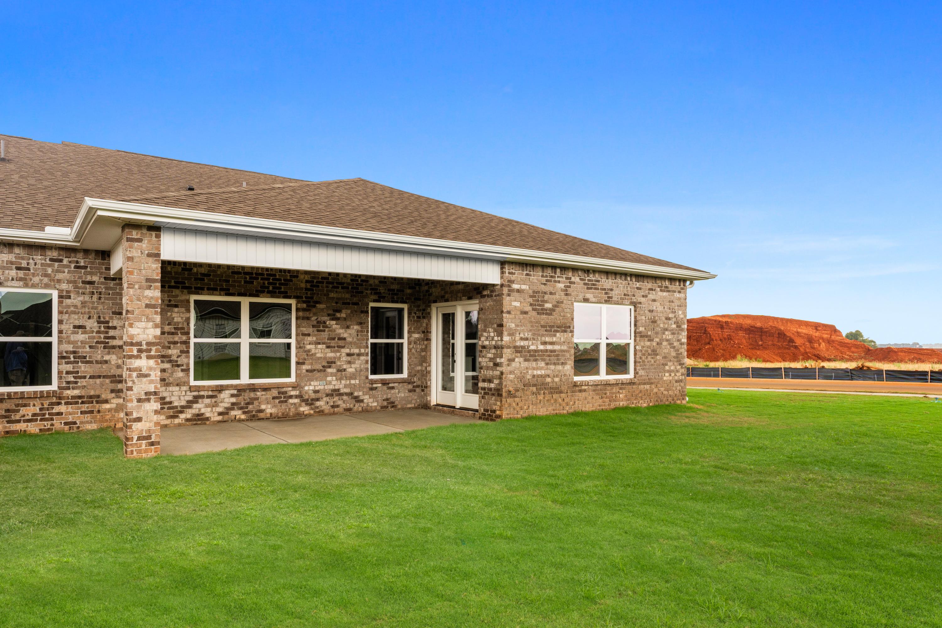 Brick home exterior at The Villas at Barnett's Crossing in Madison Alabama with covered side porch and lush green yard