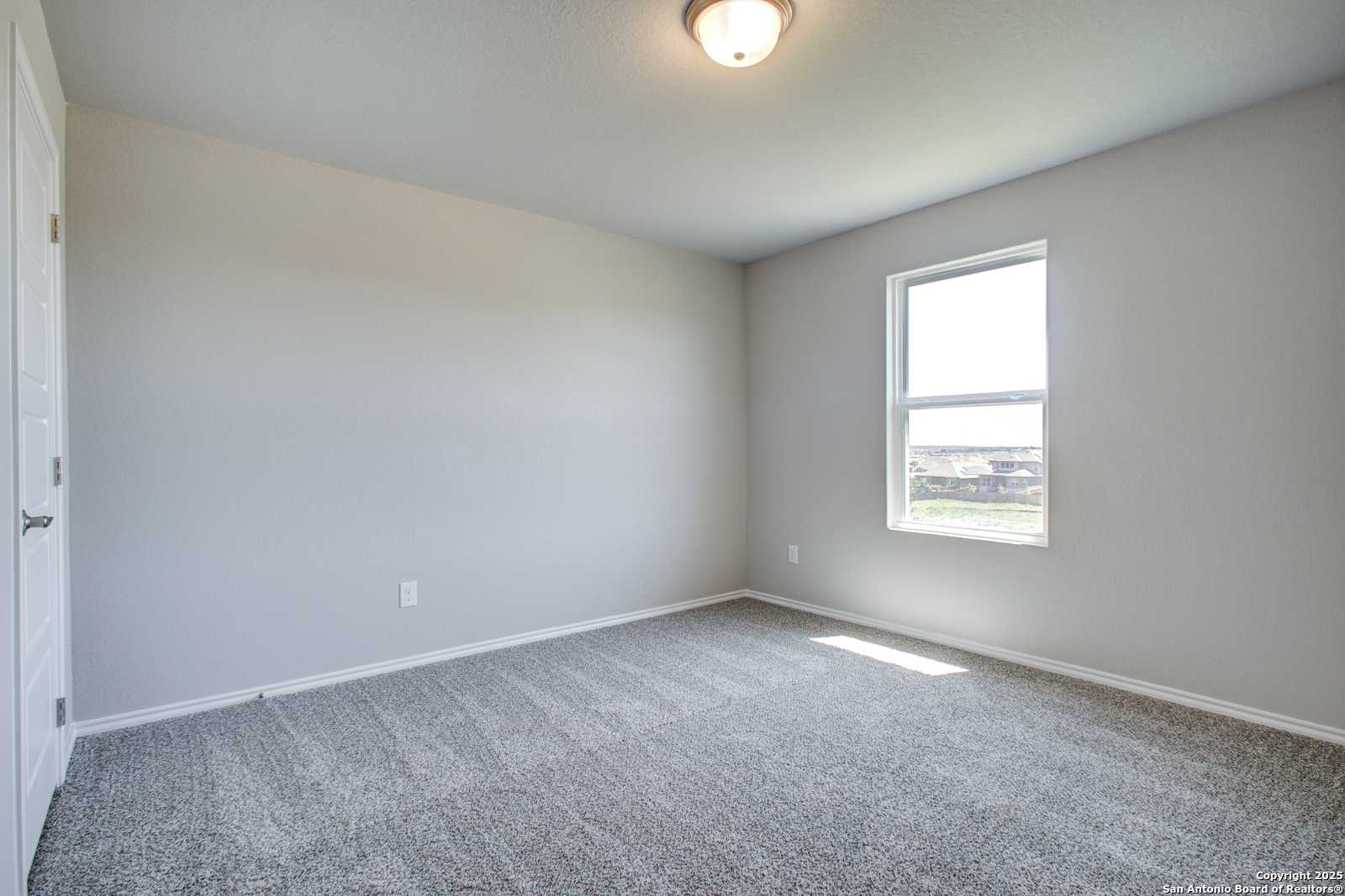 Bright secondary bedroom with light gray walls, plush carpet, and sunny window in Davidson Homes The Douglas G, San Antonio