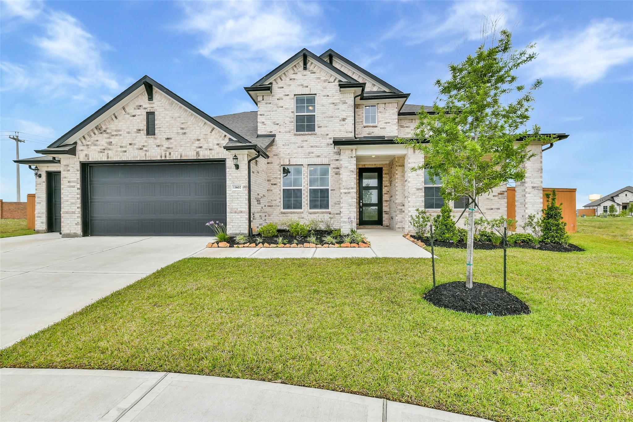 Modern two-story white brick home with 4-car garage, landscaped front yard, and driveway in Lago Mar, Texas City - Davidson Homes Victoria A
