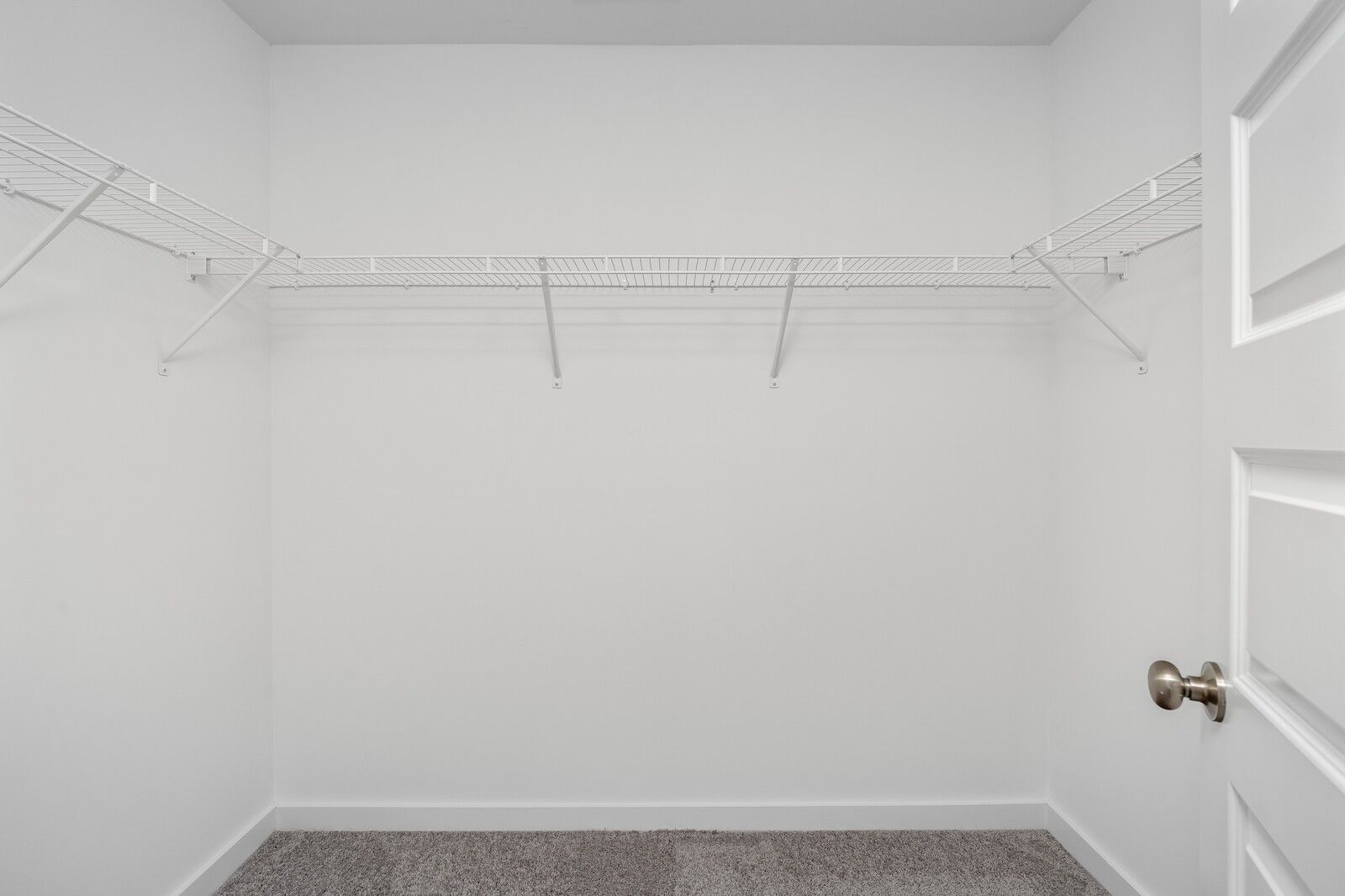 Spacious walk-in closet with white wire shelving and hanging rods in Davidson Homes The Cumberland A, Gallatin, TN