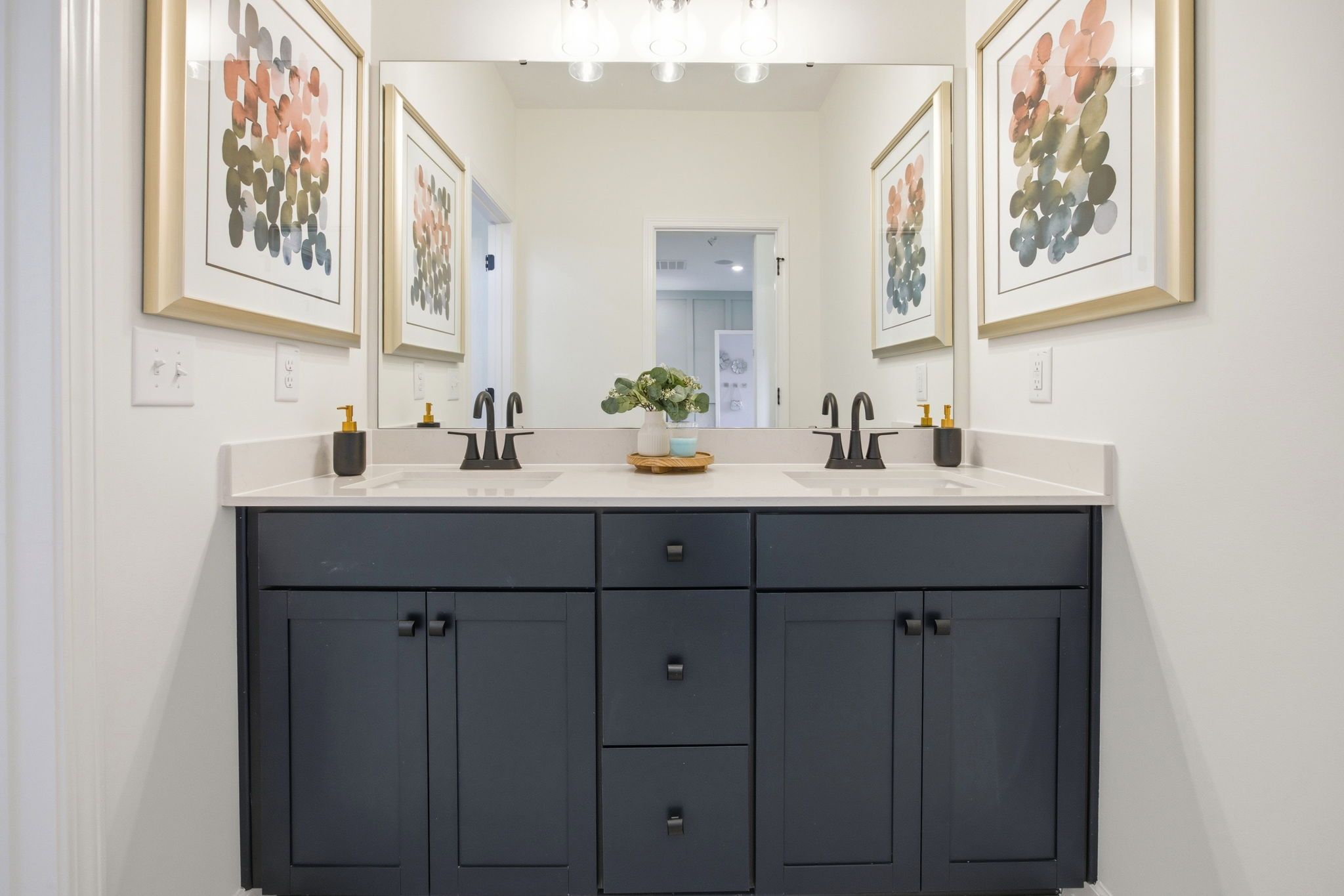 Modern double vanity in The Ashport master bath featuring dark navy cabinetry, matte black fixtures, and quartz countertops.