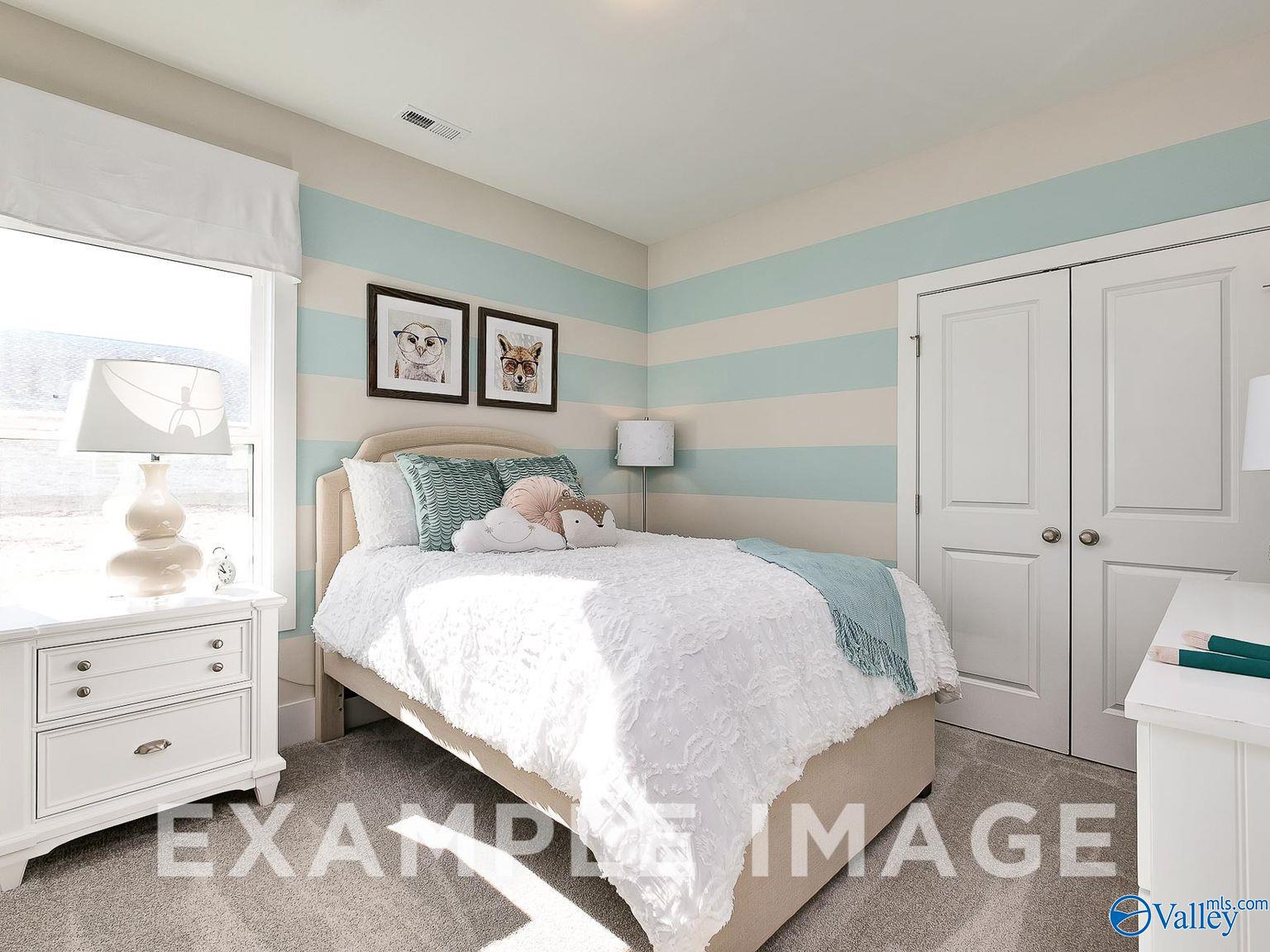 Cozy girl's bedroom with aqua striped walls, plush twin bed, teddy bear, dog art, and desk in Davidson Homes Everett B, Toney, Alabama