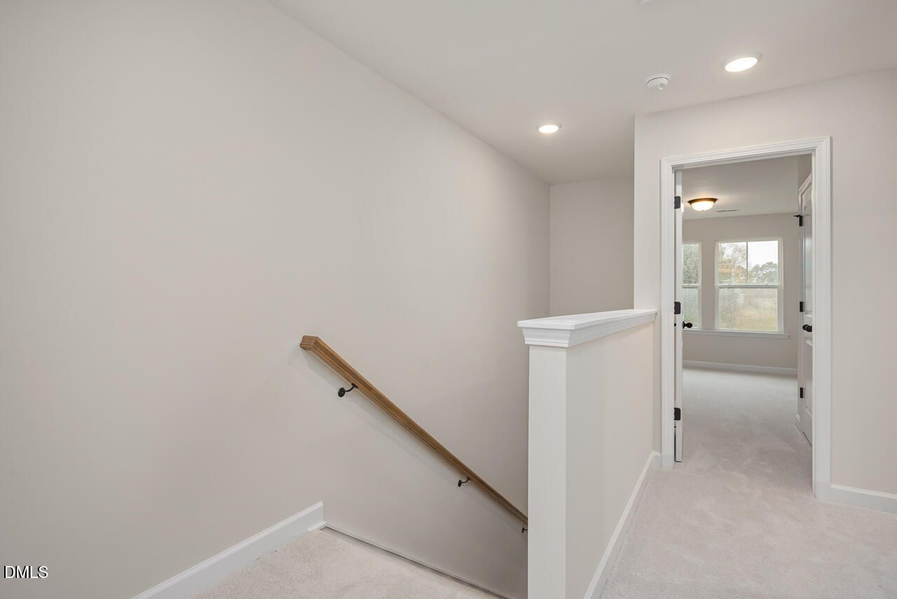 Elegant wooden handrail and white balustrade overlooking carpeted hallway in 4-bedroom The Mitchell home, Knightdale, NC