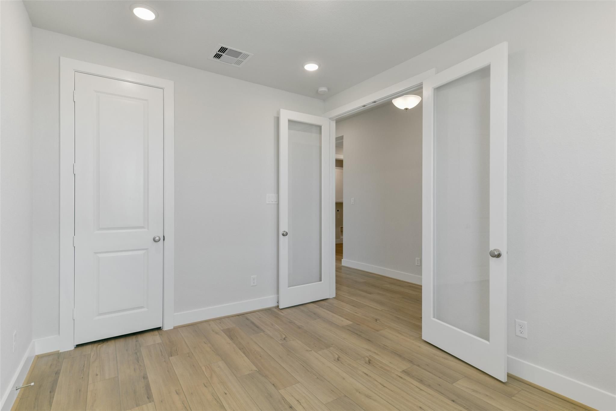 Bright entryway with light oak floors, white trim doors, and frosted glass panels in The Edward A floor plan, Lago Mar, Texas City