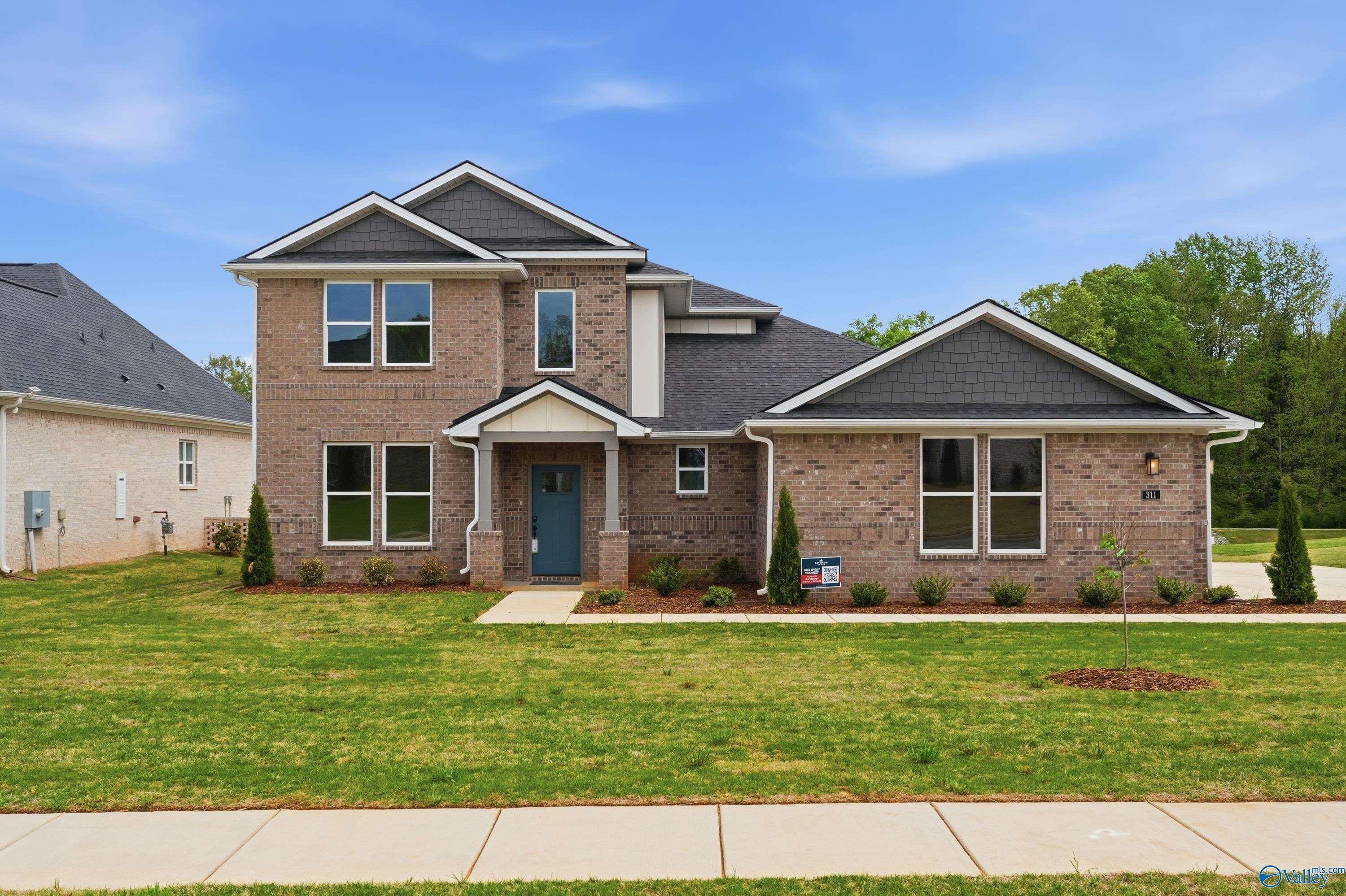 Two-story brick home with blue front door, gray shingle roof, and landscaped yard in Riverton Preserve, Huntsville, Alabama