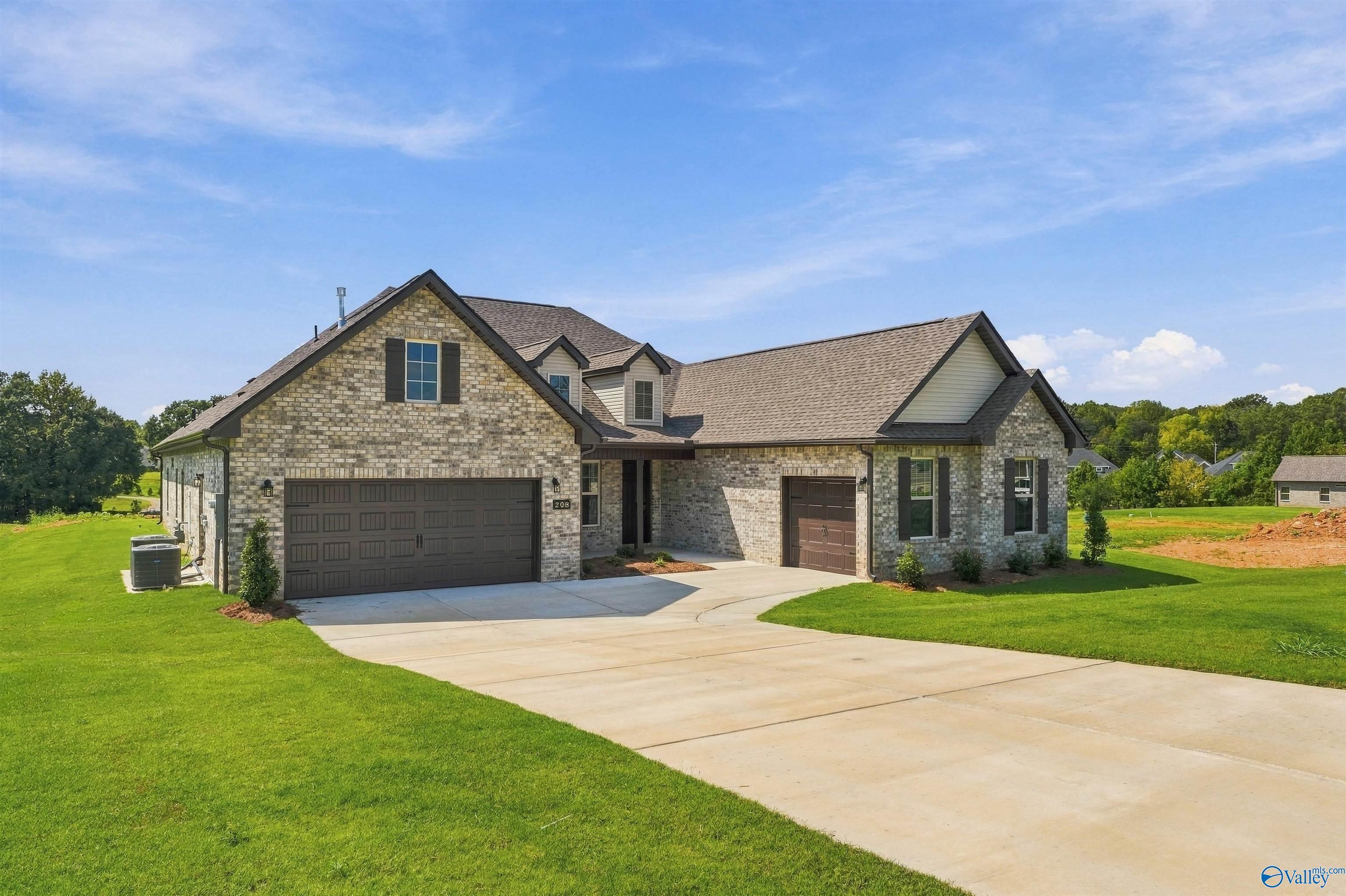 Brick front exterior with 3-car garage and curved driveway at Davidson Homes' The Valencia in Riverton Preserve, Huntsville, Alabama