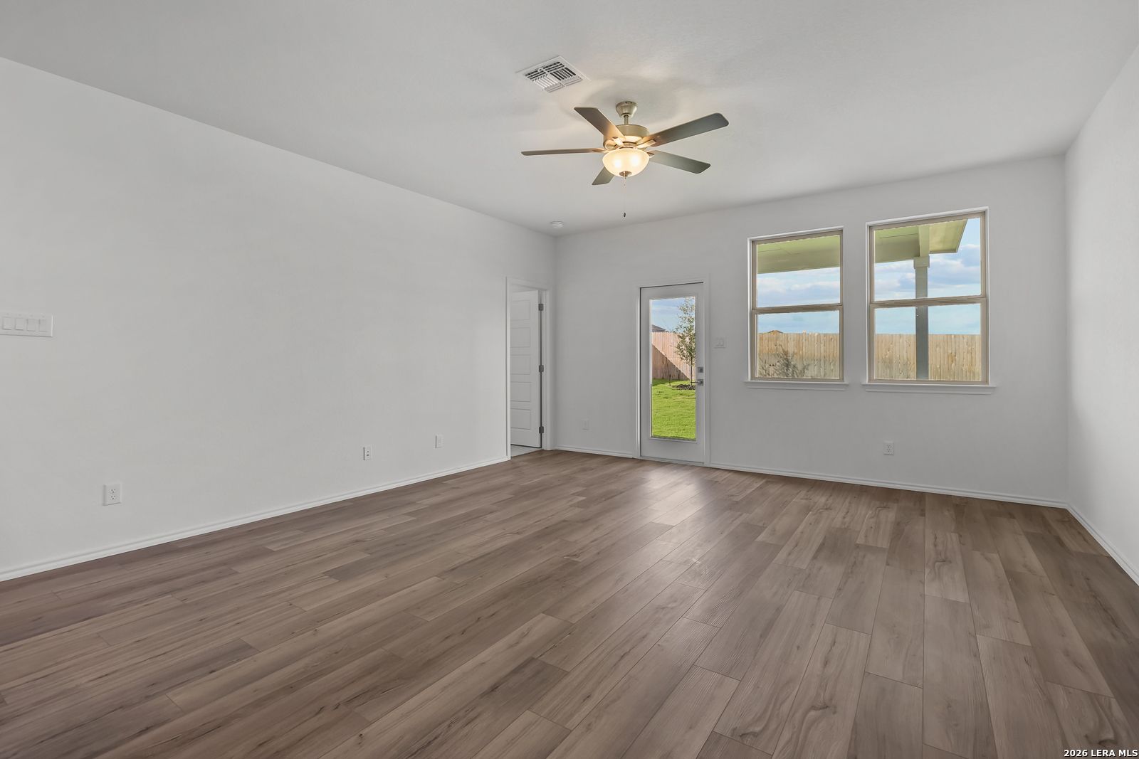 Spacious living area with wood-look flooring and ceiling fan in The Brazos B floor plan by Davidson Homes in Agave, SA.