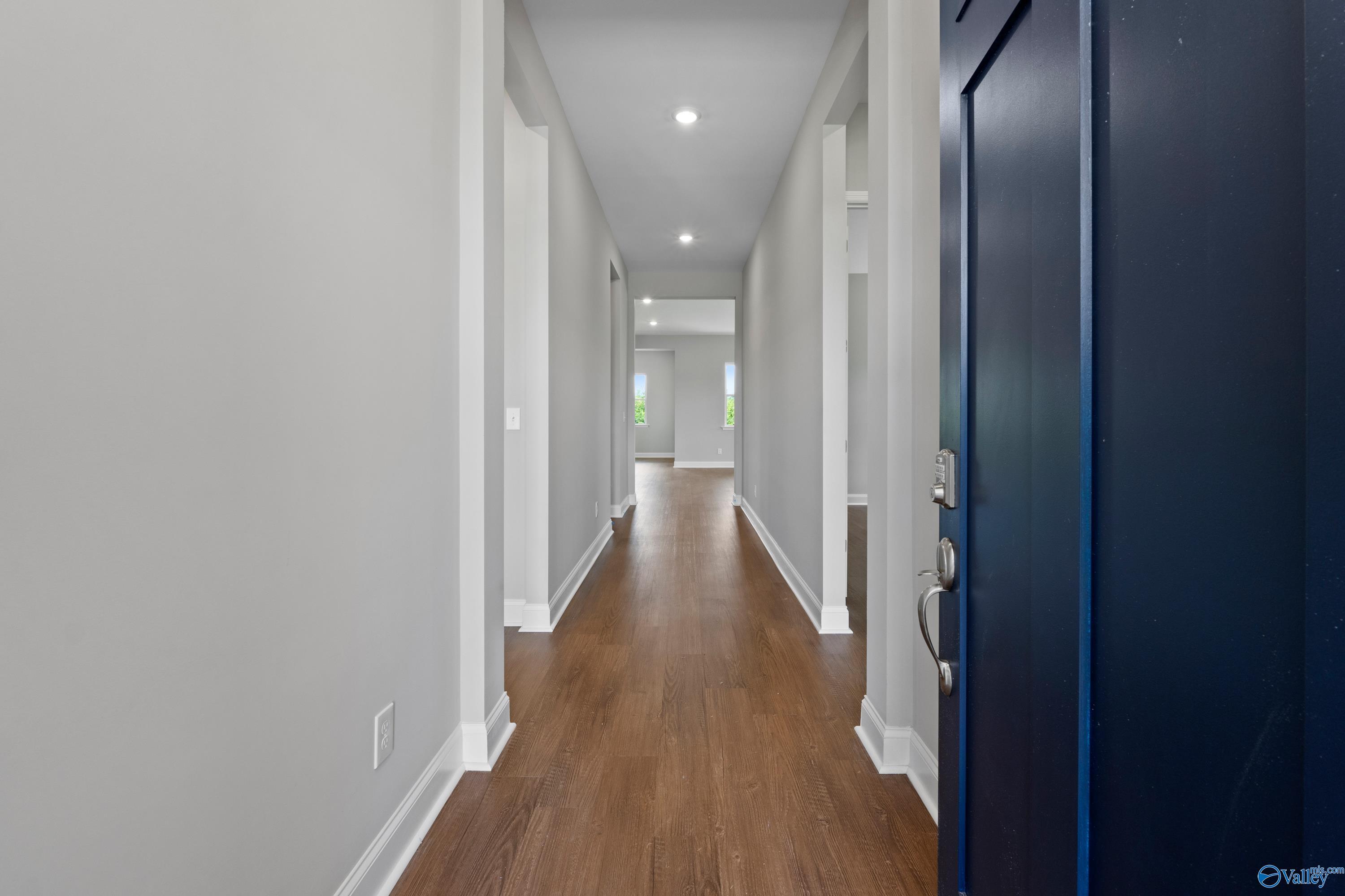 Long hallway with light gray walls, hardwood floors, and navy blue door in Davidson Homes Arcadia B, Riverton Preserve, Huntsville