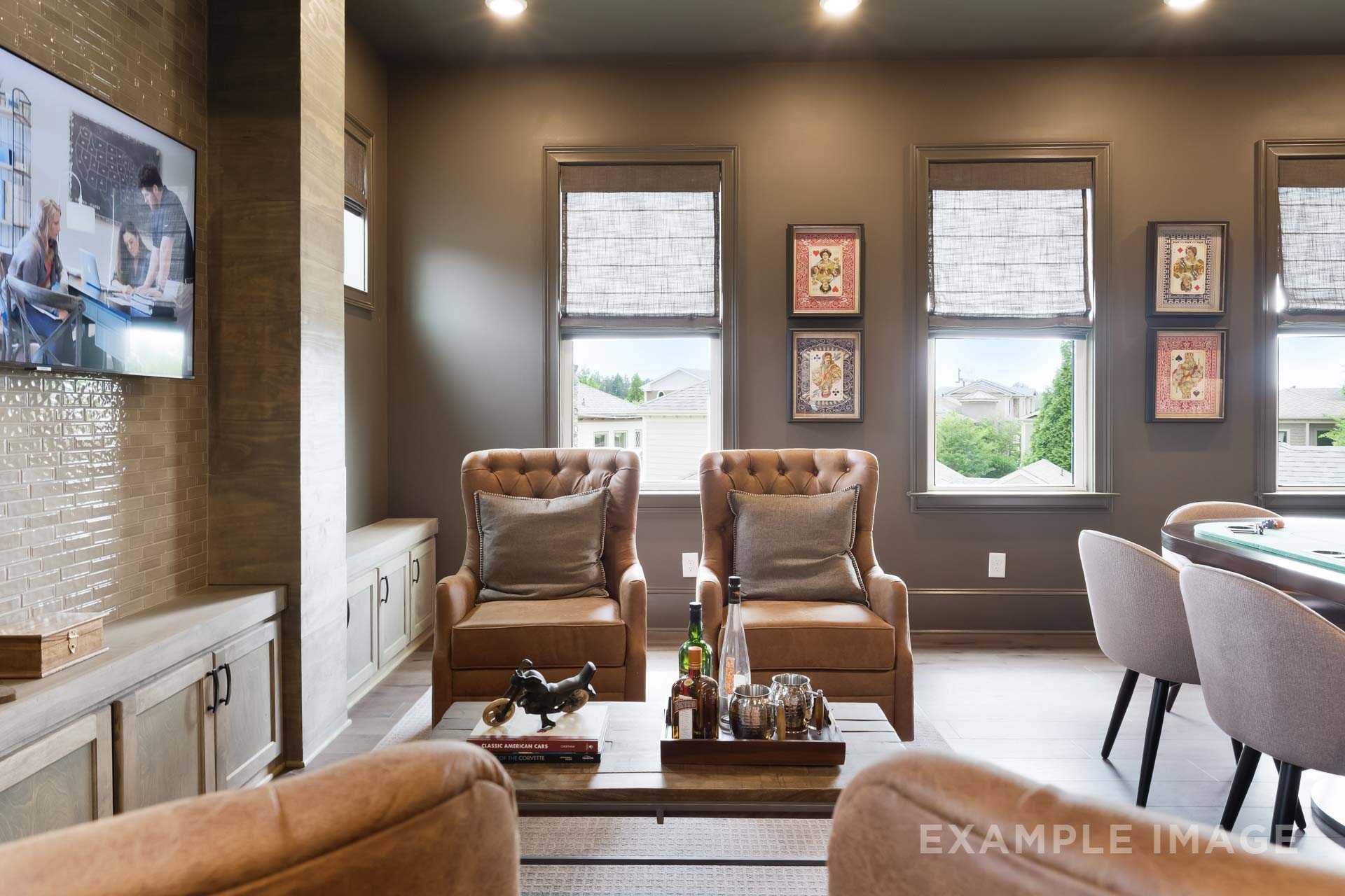Spacious game room in The Seaside by Davidson Homes, Woodstock GA, featuring leather armchairs, poker table, mounted TV, and large windows