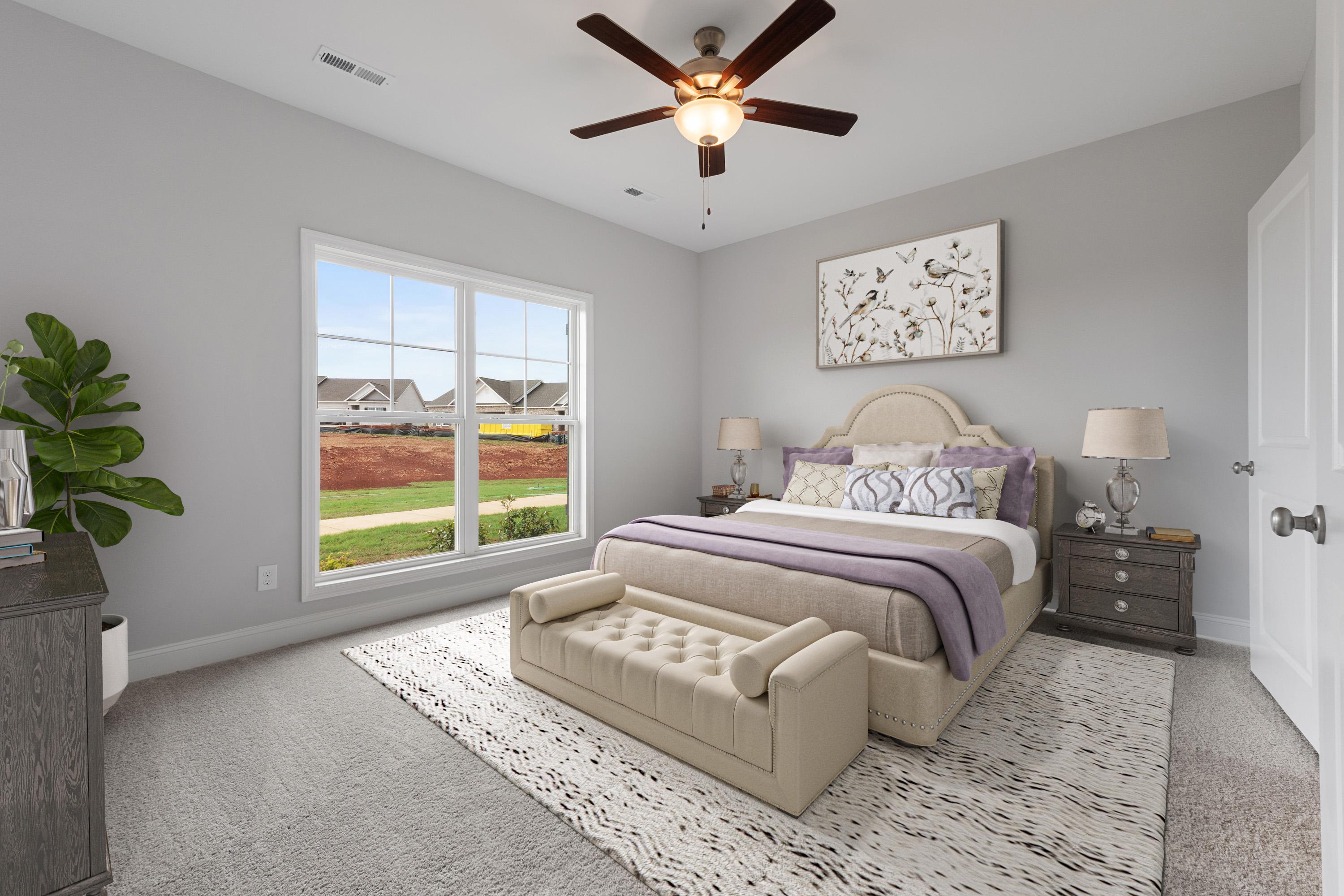 Serene master bedroom at The Villas at Barnett's Crossing in Madison, Alabama with tufted bed, large window overlooking neighborhood, and modern gray decor