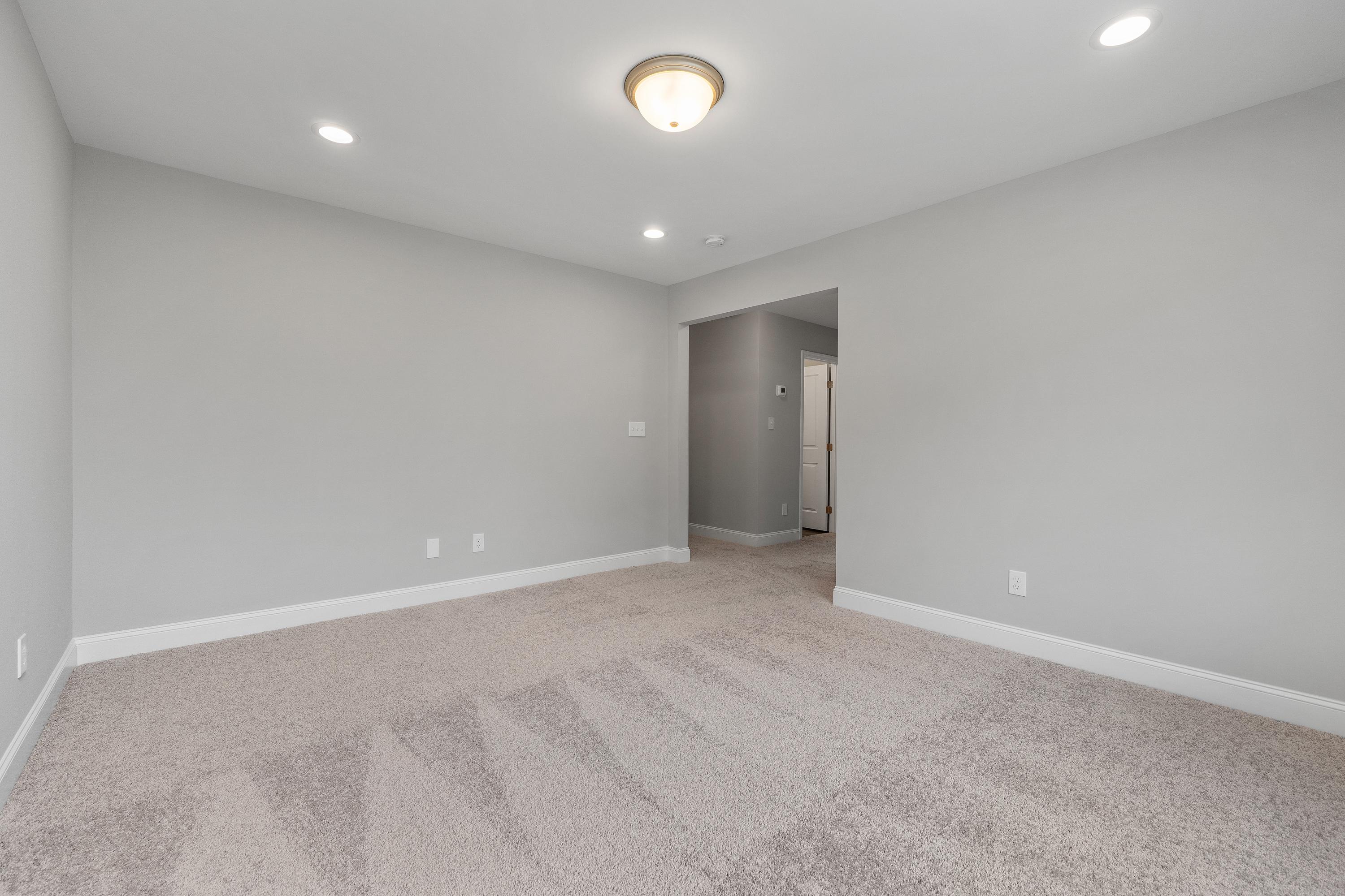 Spacious empty bonus room in The Aiken by Davidson Homes with gray walls, beige carpet, recessed lights