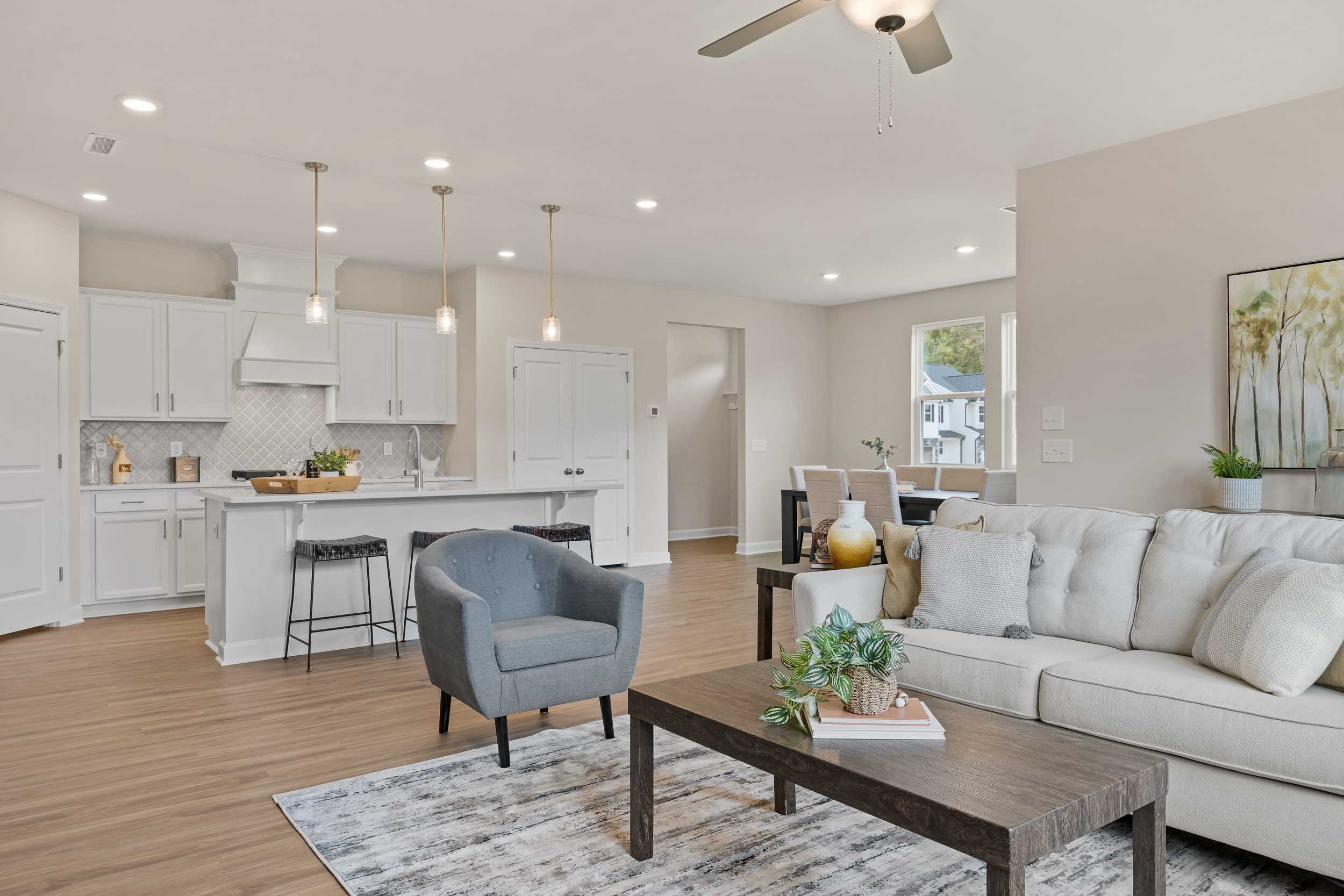 Spacious open-concept living room and kitchen in Gregory Village, Lillington NC with white cabinets, hardwood floors and modern decor