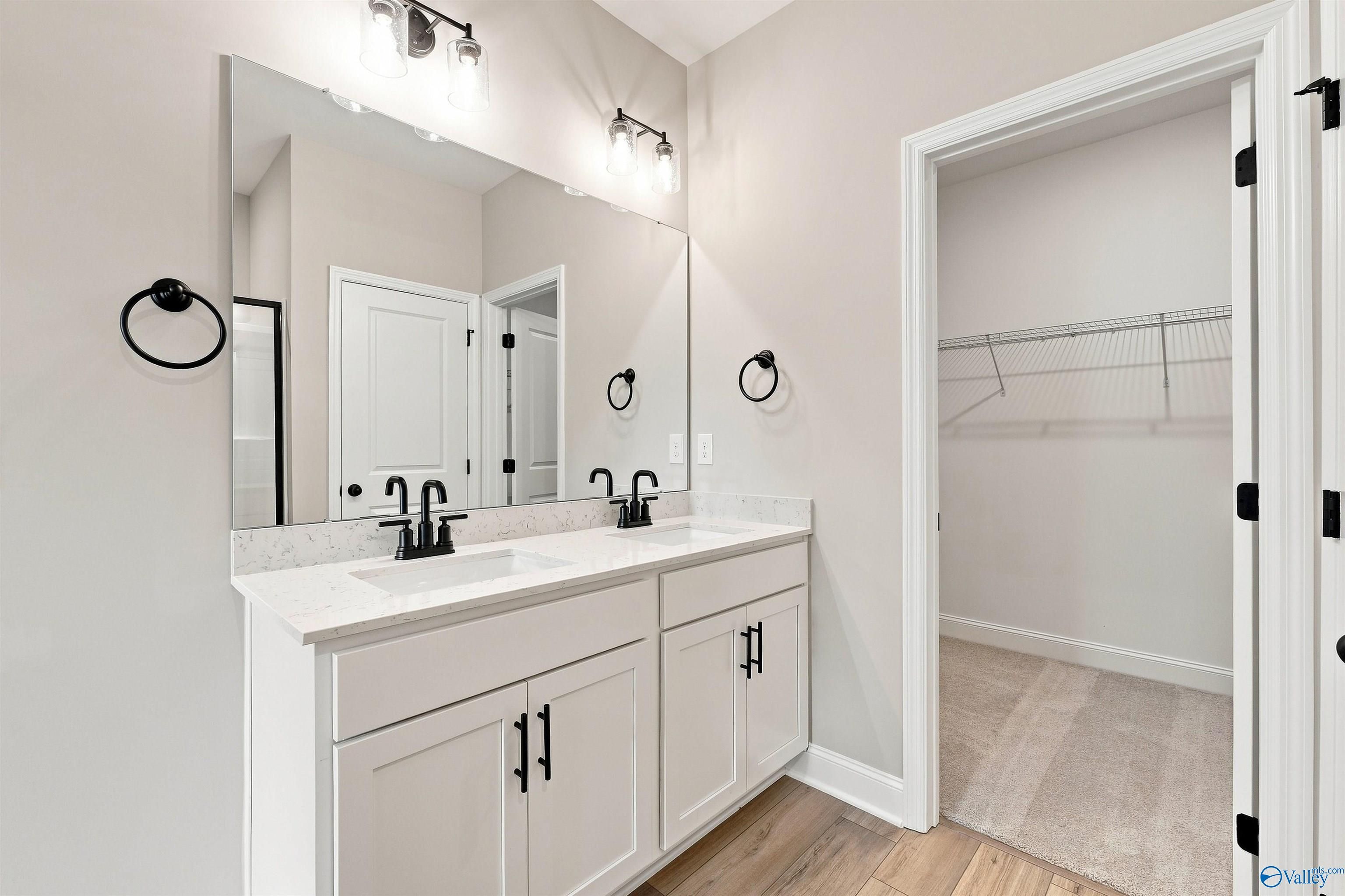 Dual vanity bathroom with white cabinets, black fixtures, quartz countertops, and walk-in closet in Davidson Homes Franklin C plan, Toney AL