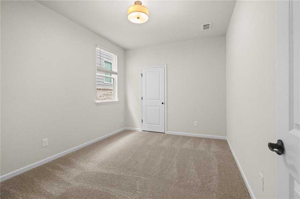 Bright secondary bedroom with beige walls, tan carpet, window blinds in The Glenwood A by Davidson Homes, Loganville, GA