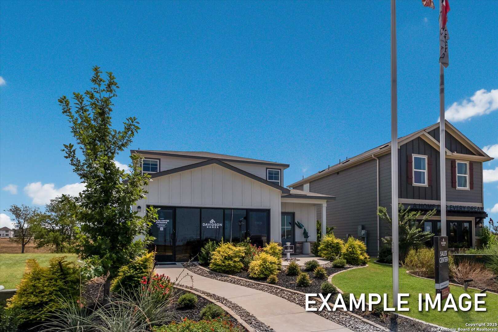 Modern two-story Sabine B home exterior with white siding, two-car garage, landscaped front yard, and flagpole in Agave, San Antonio, Texas