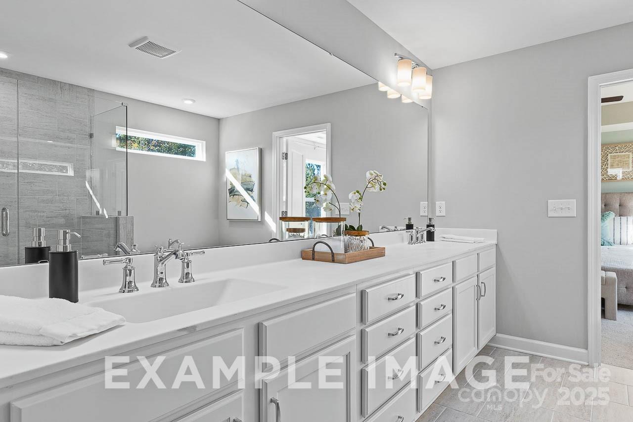 Luxurious master bathroom with double vanity, frameless glass shower, and soft lighting in Davidson Homes The Hemlock A, Belmont, NC