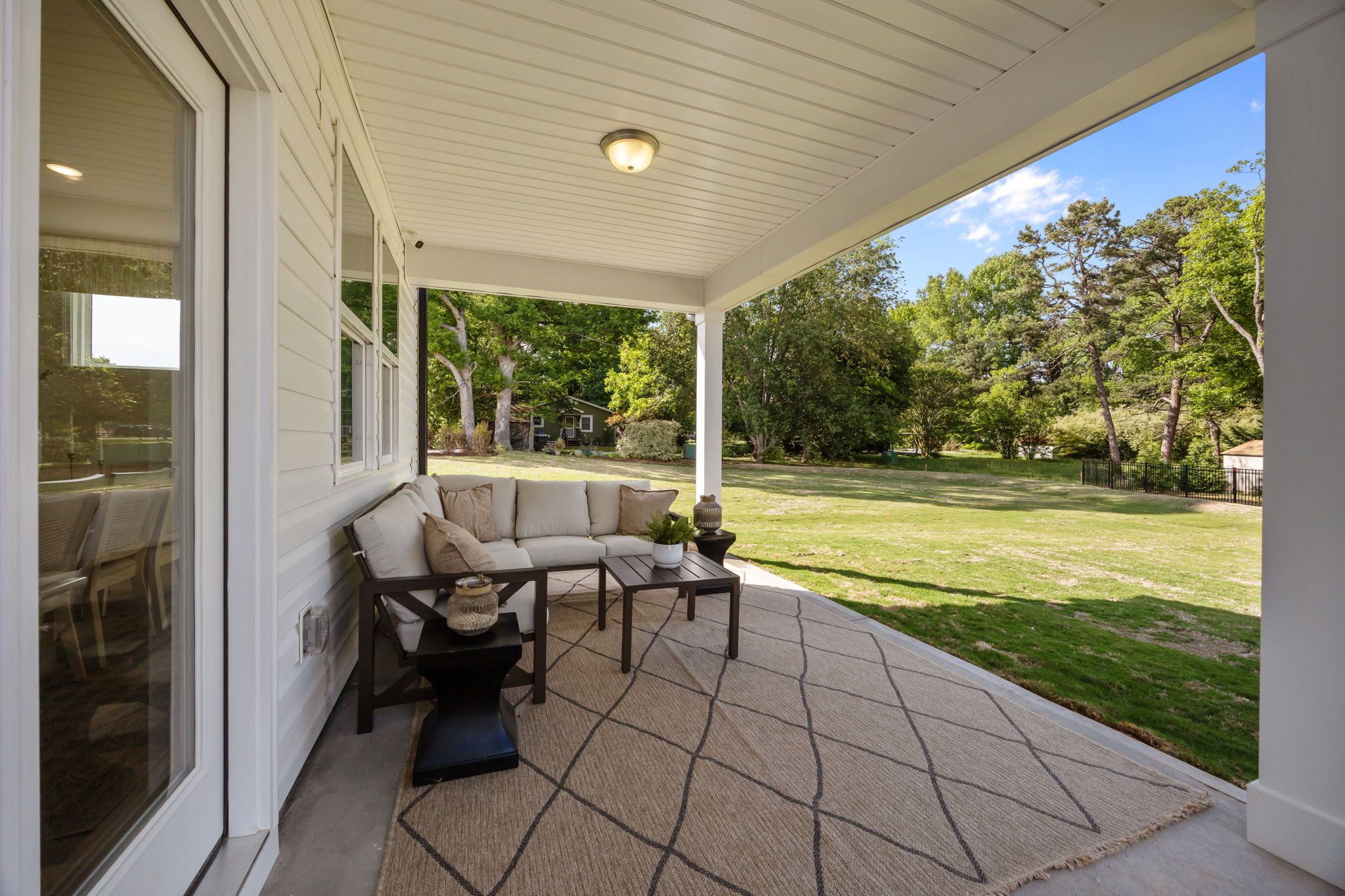 Covered patio with outdoor lounge seating at Springvale South in Fuquay-Varina, NC by Davidson Homes overlooking backyard.