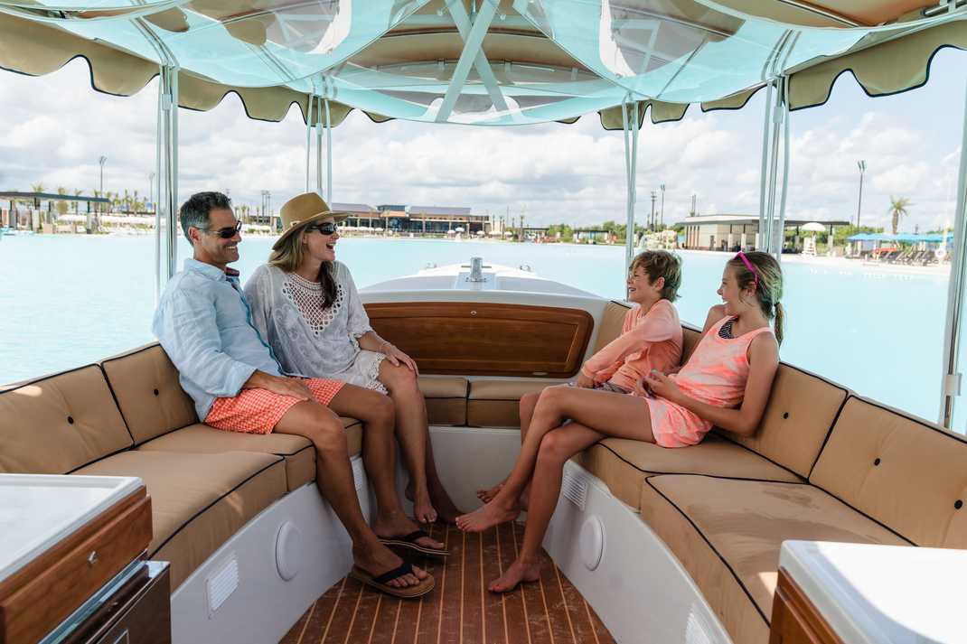 Family of four relaxing on covered pontoon boat in turquoise lagoon at Lago Mar, Texas City, Texas by Davidson Homes