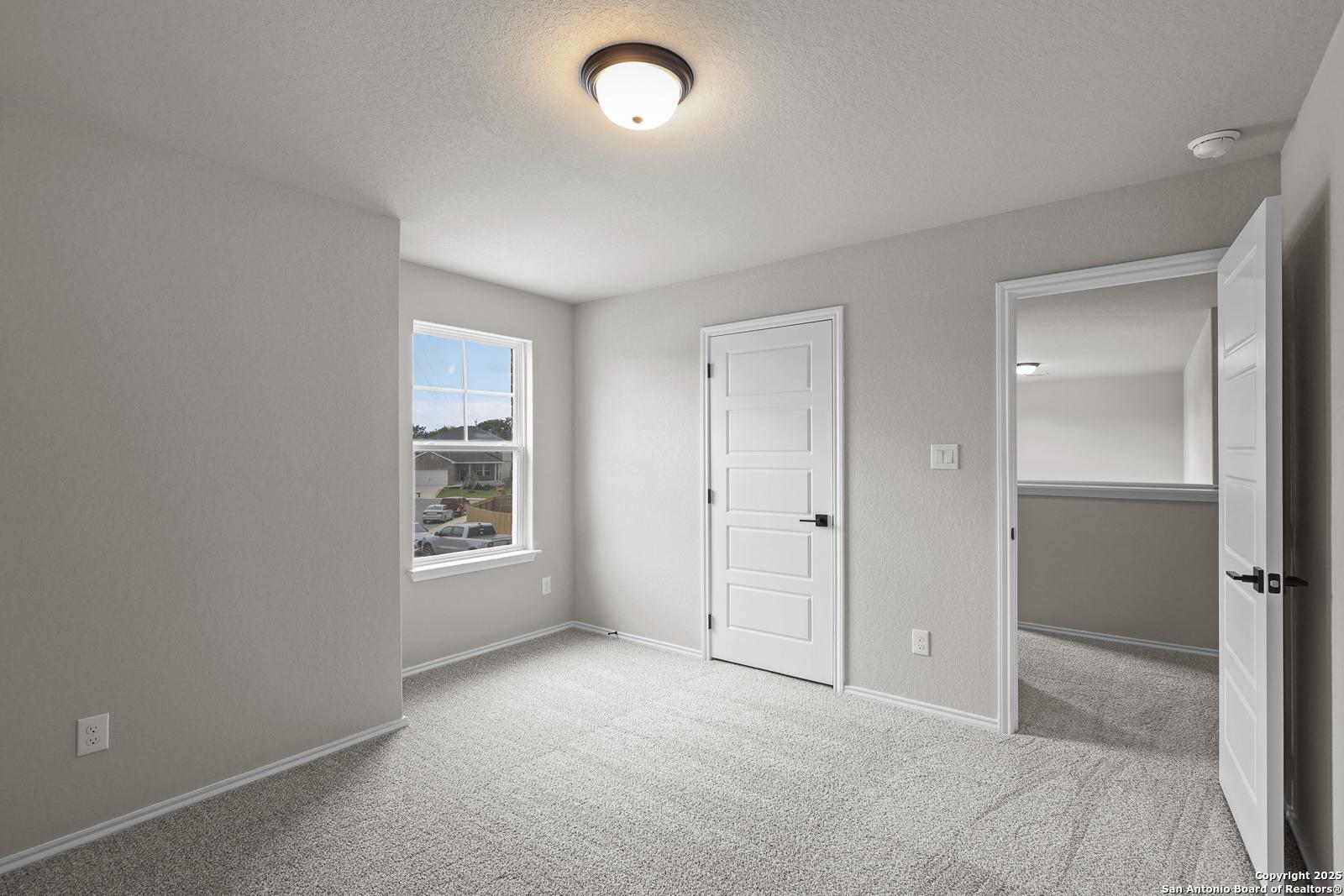 Bright secondary bedroom with gray walls, plush carpet, white doors, and window in Davidson Homes The Murray J, San Antonio